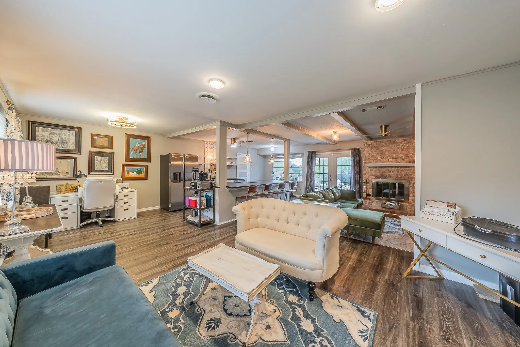 Wood-finish flooring throughout, brick fireplace with mantel, recessed lighting, and exposed ceiling beams