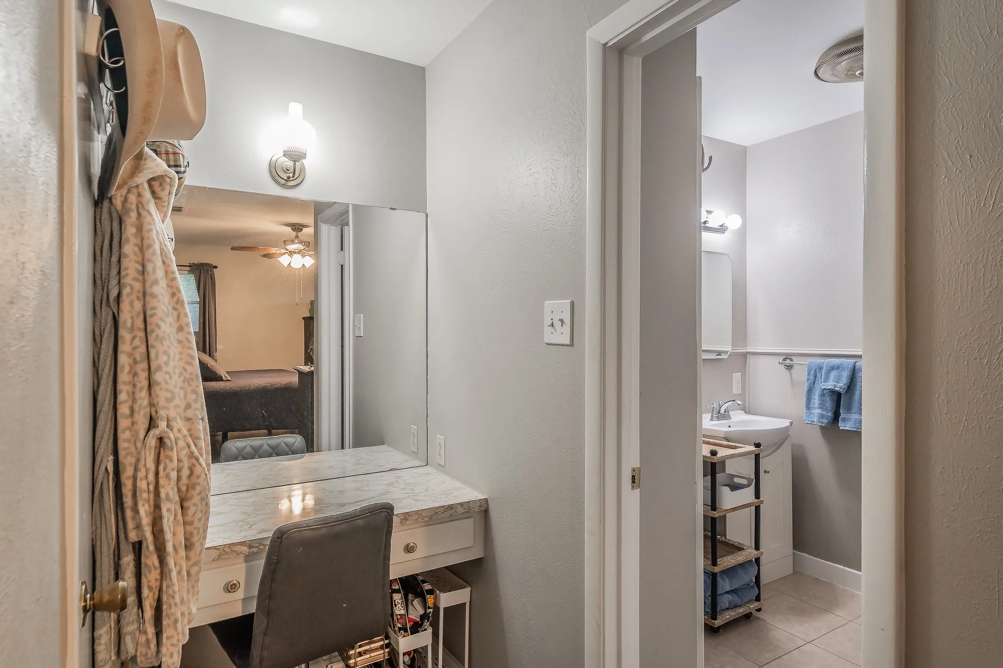 Vanity area with a built-in countertop, wall mirror, and sconce lighting