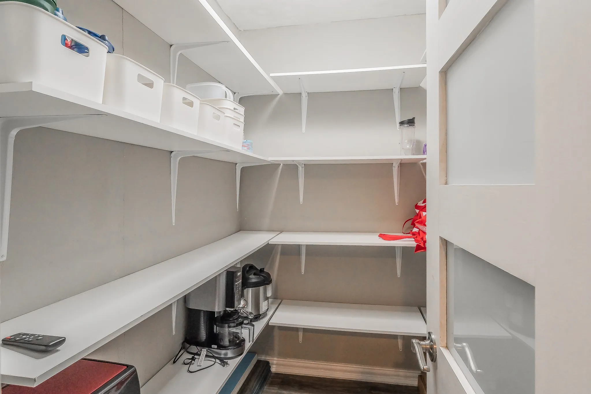 Built-in shelving with L-shaped configuration, white finishes, and a framed door with frosted glass panels