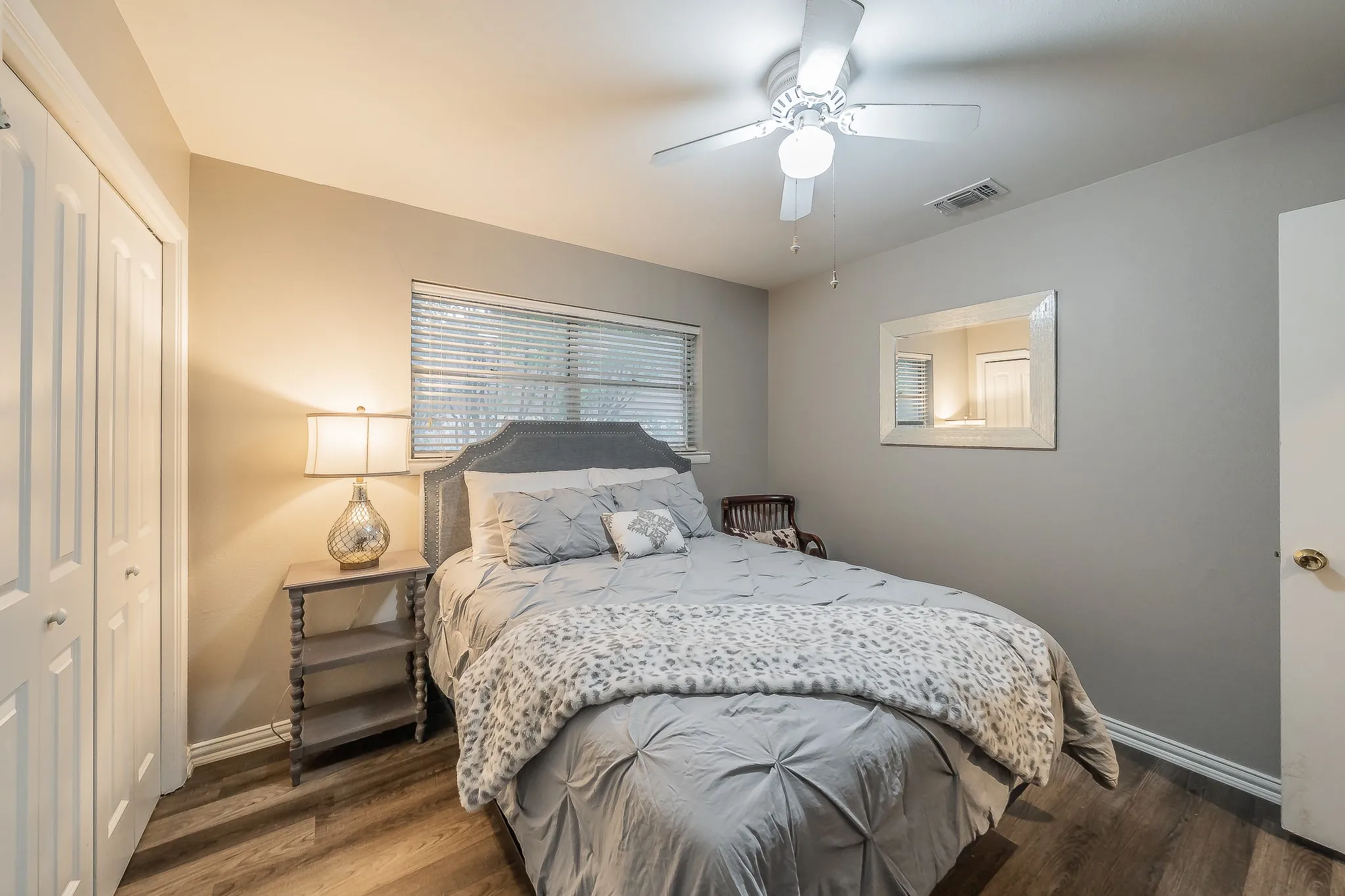 Wood-finish flooring, ceiling fan with integrated lighting, window with blinds, and bi-fold closet doors