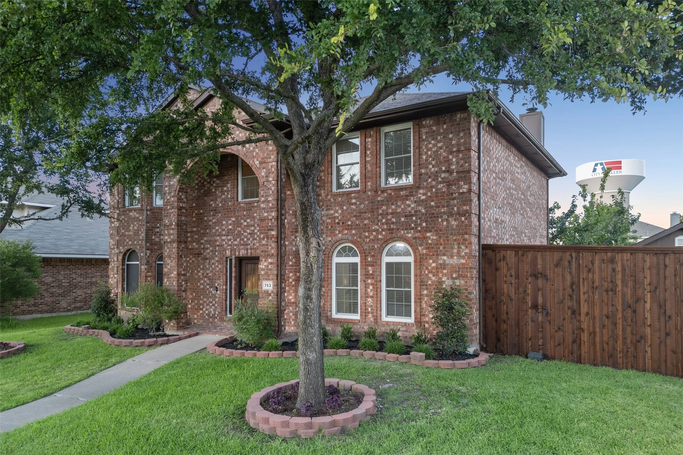 Brick exterior with arched entry, arched windows, and a wood privacy fence