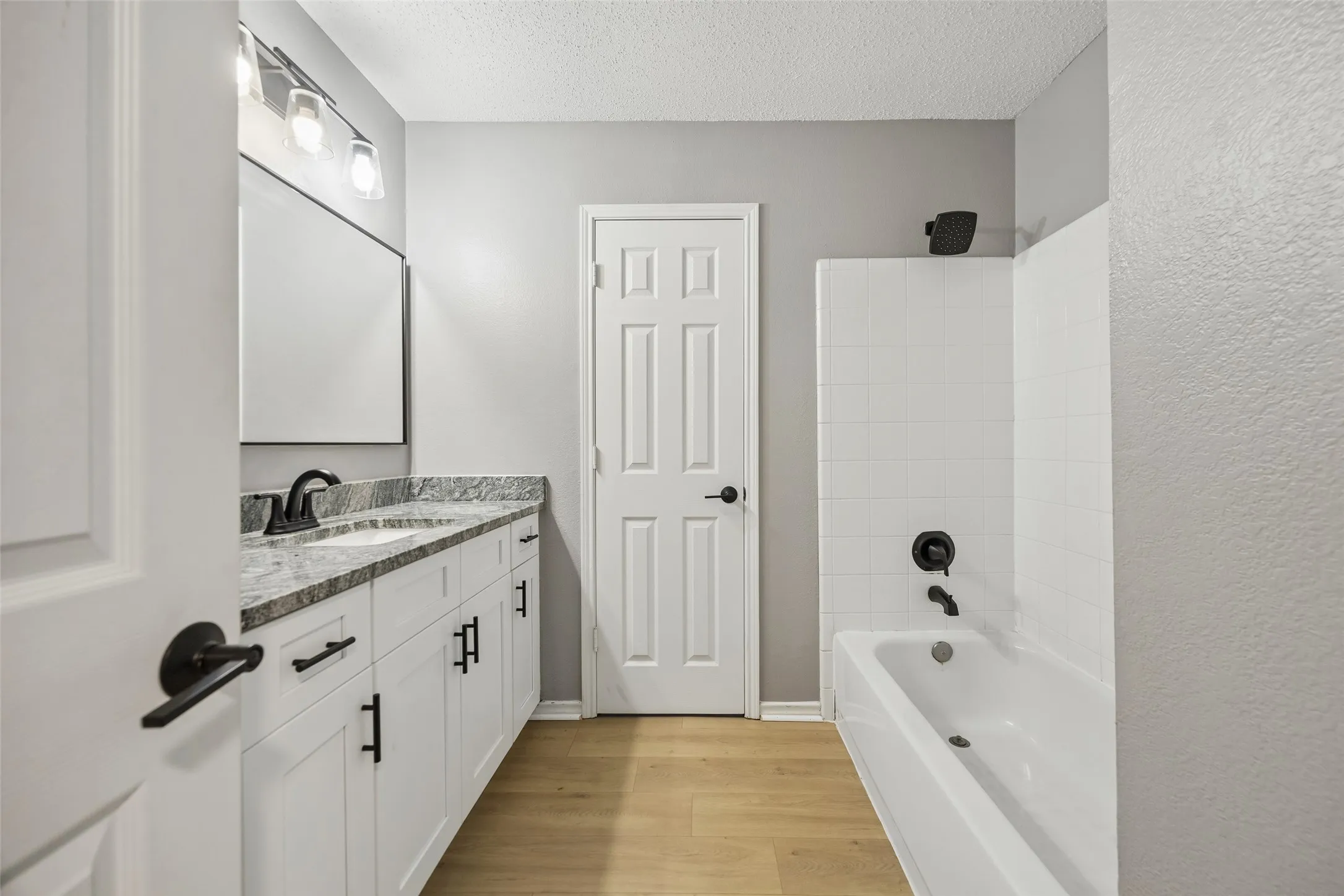 White vanity with dark hardware, granite-style countertop, and rectangular sink