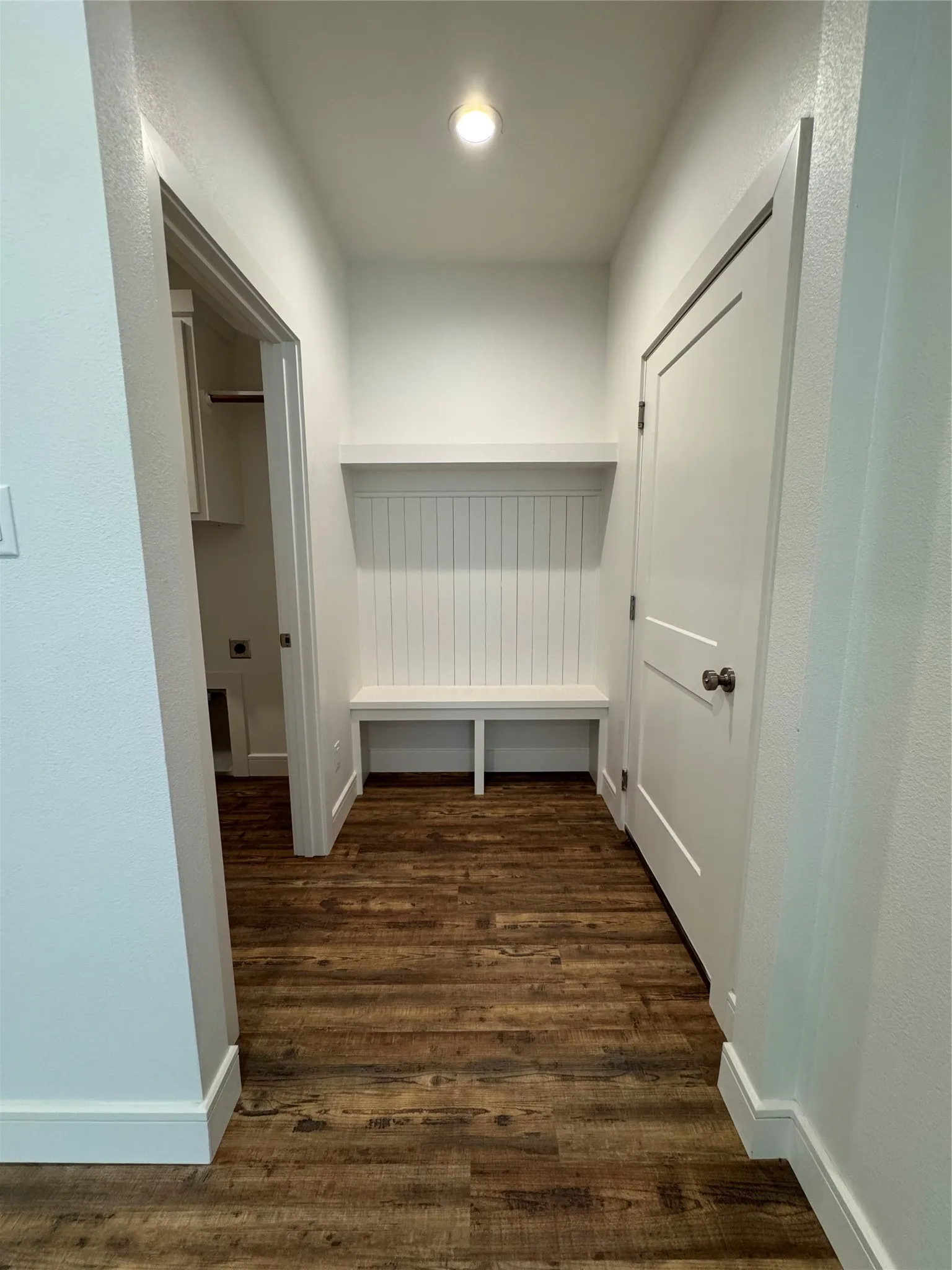Entryway featuring wood-finish flooring, built-in bench, wall-mounted shelf, beadboard wall paneling, and white interior doors