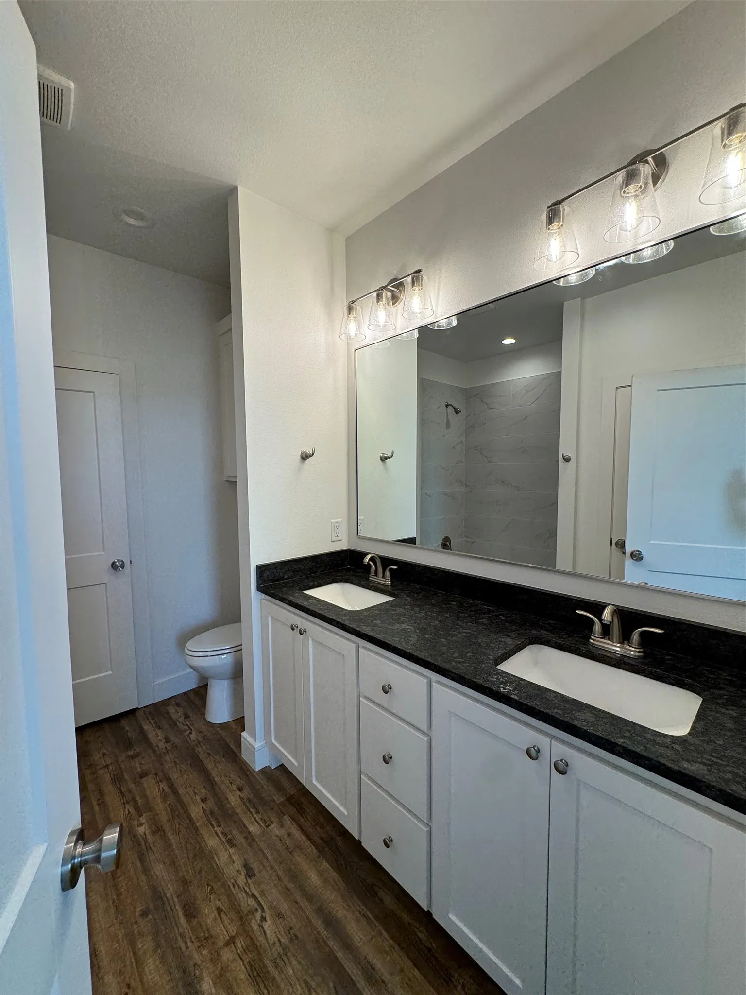 Dual vanity with dark stone-finish countertop, undermount sinks, and brushed nickel fixtures