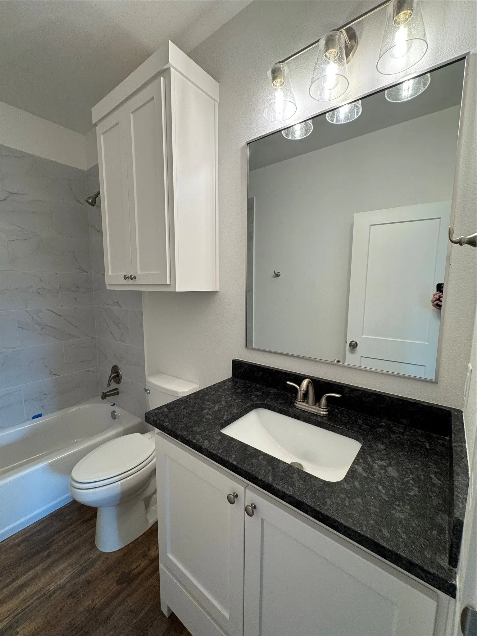 White vanity with dark stone countertop, undermount sink, and brushed nickel faucet