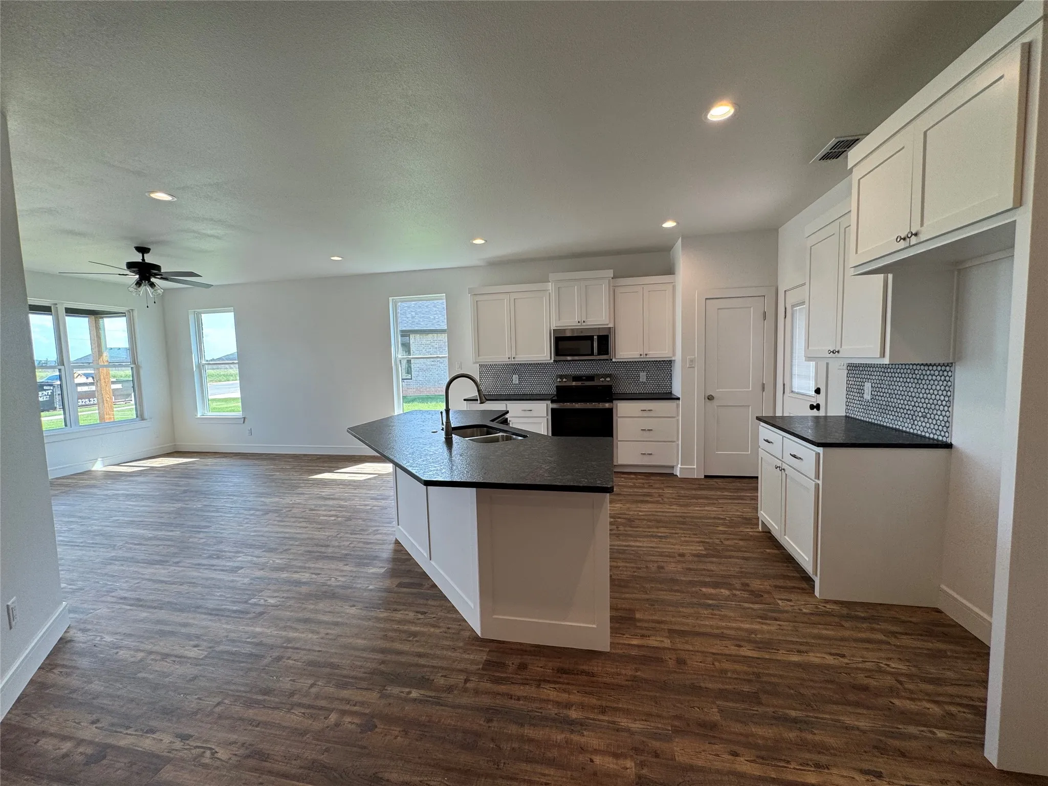 Open-concept living space with wood-finish flooring, recessed lighting, and a ceiling fan