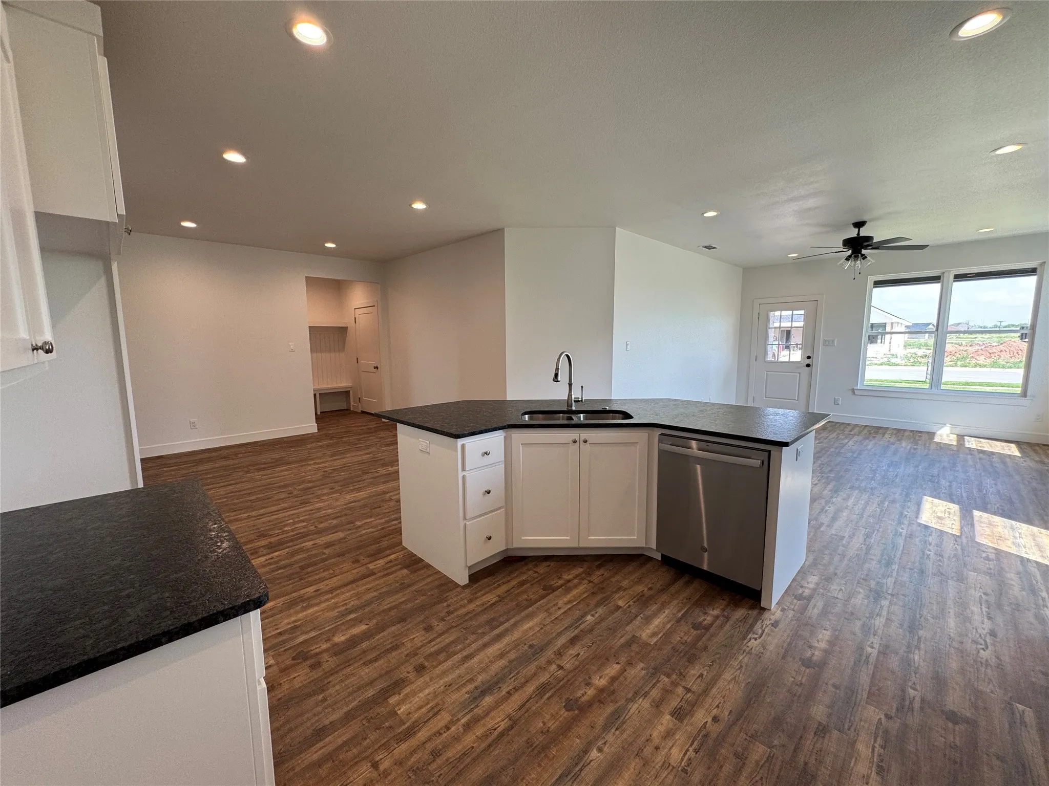 Kitchen island with dark countertop, integrated sink, and stainless steel dishwasher