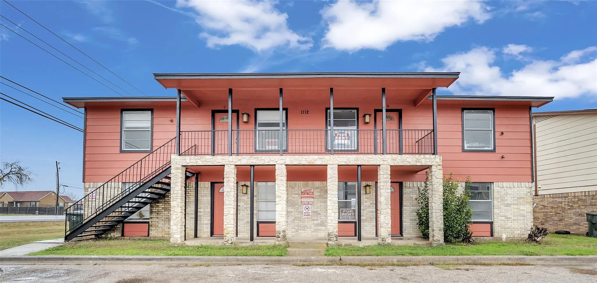 Two-story apartment building with a coral exterior and stone-clad first level
