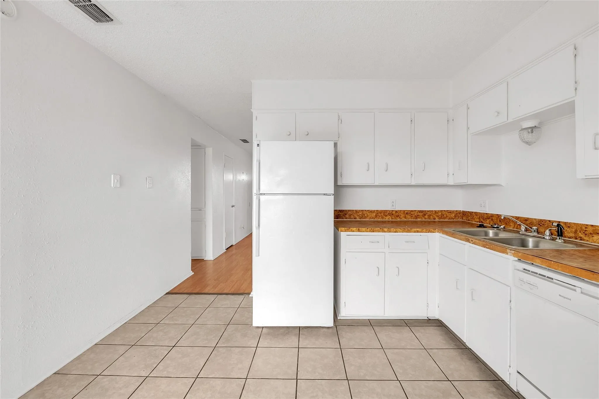 Kitchen featuring white cabinetry, white appliances, dual basin sink, and tiled flooring