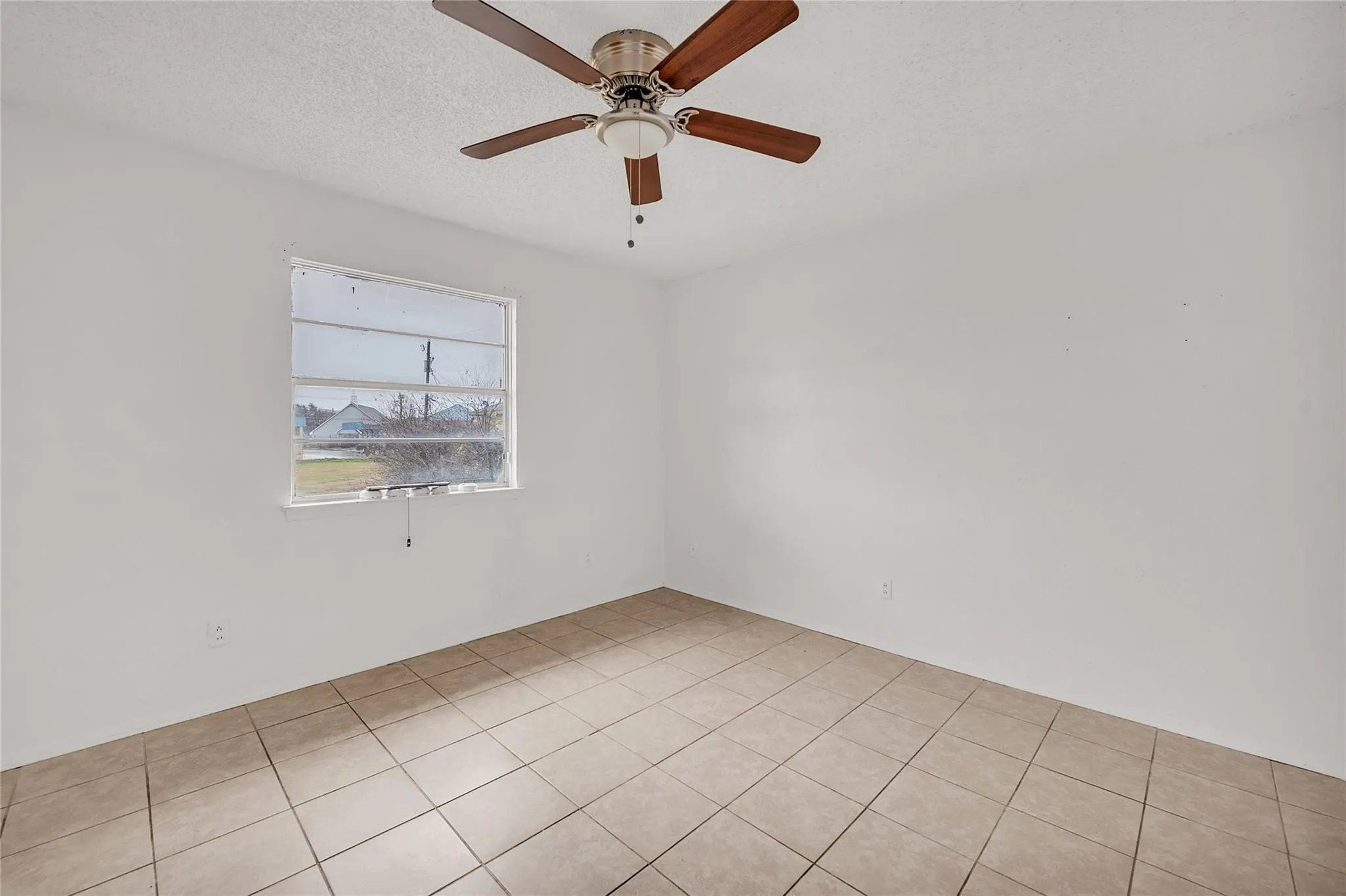 Light-toned tile flooring, white walls, and a ceiling fan with light fixture