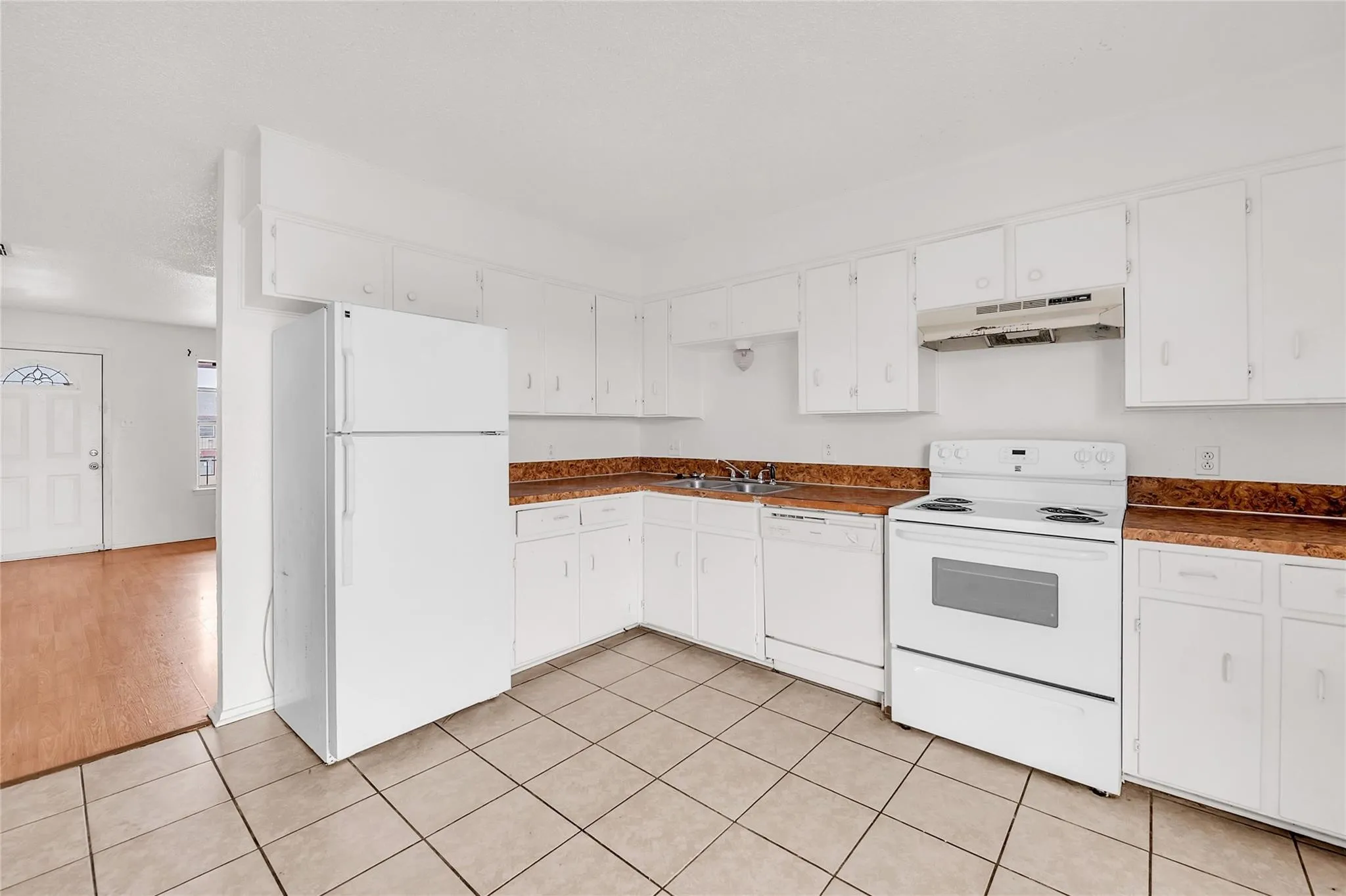 Kitchen with white cabinetry, integrated white appliances, and tiled flooring