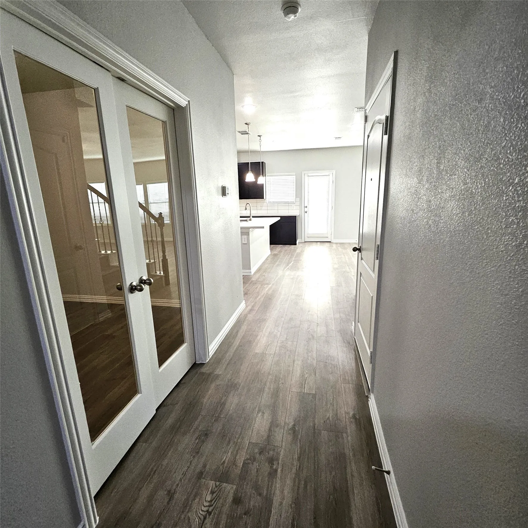 Wood-finish flooring throughout, white trim, and a light gray wall finish