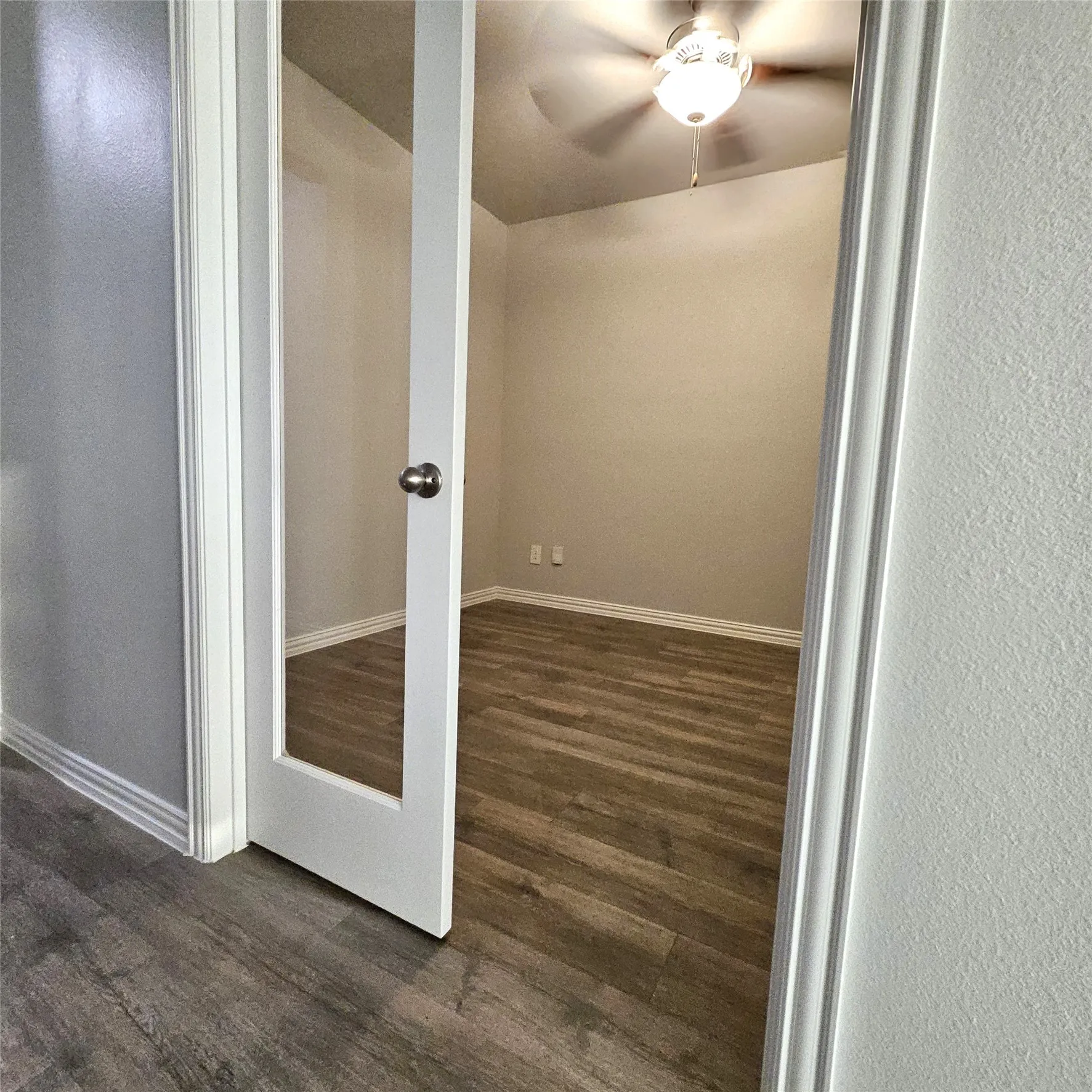 Room with wood-finish flooring, ceiling fan, and a glass-paneled entry door