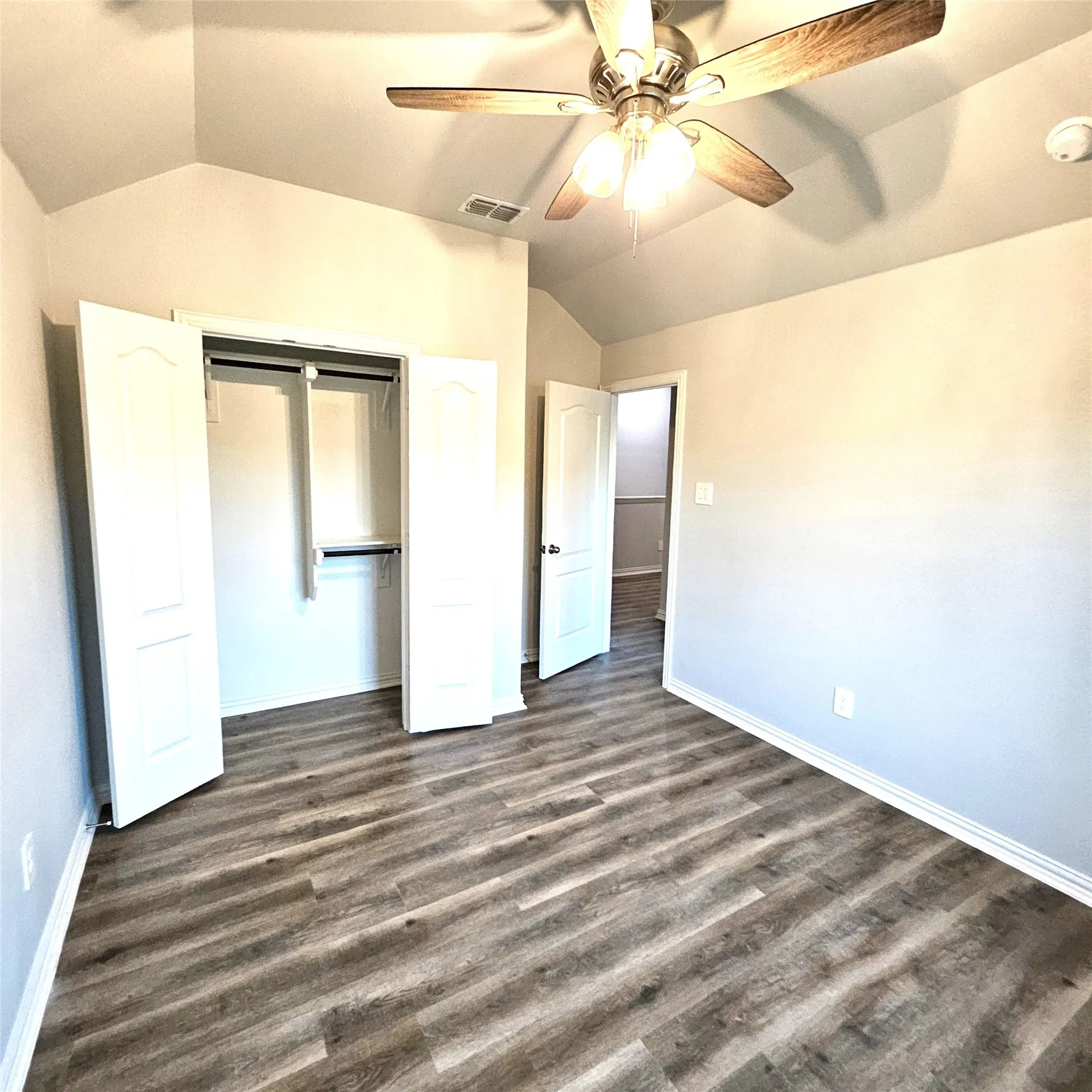Vaulted ceiling, wood-finish flooring, ceiling fan with integrated lighting, bi-fold closet doors, and recessed lighting
