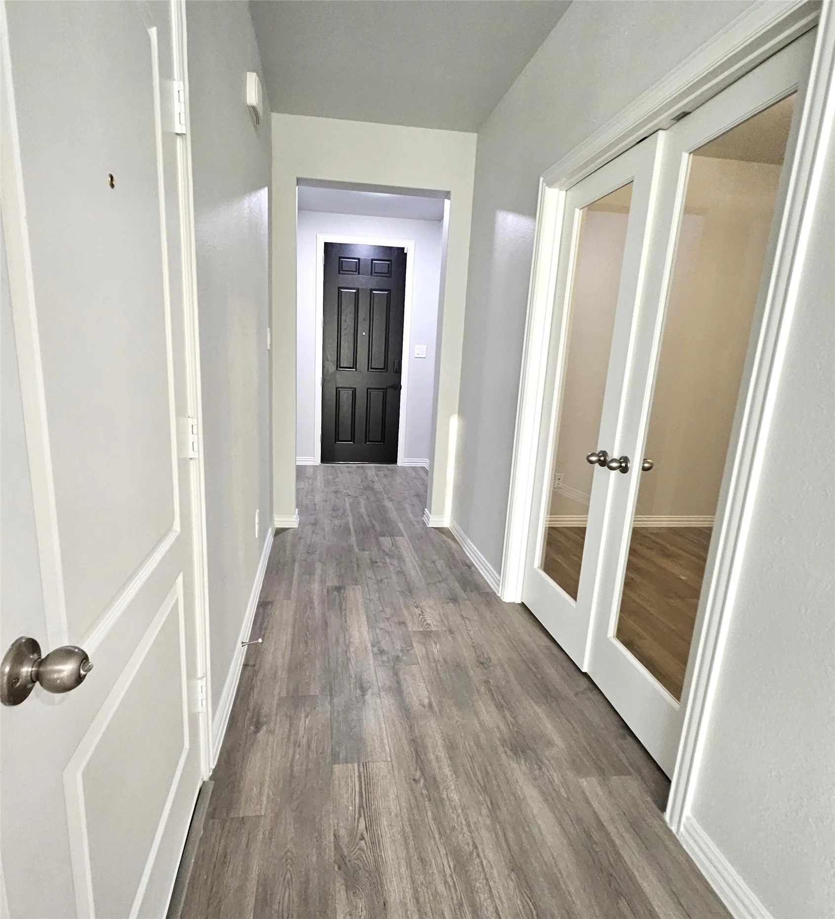 Wood-finish flooring throughout, bright white walls, and paneled doors