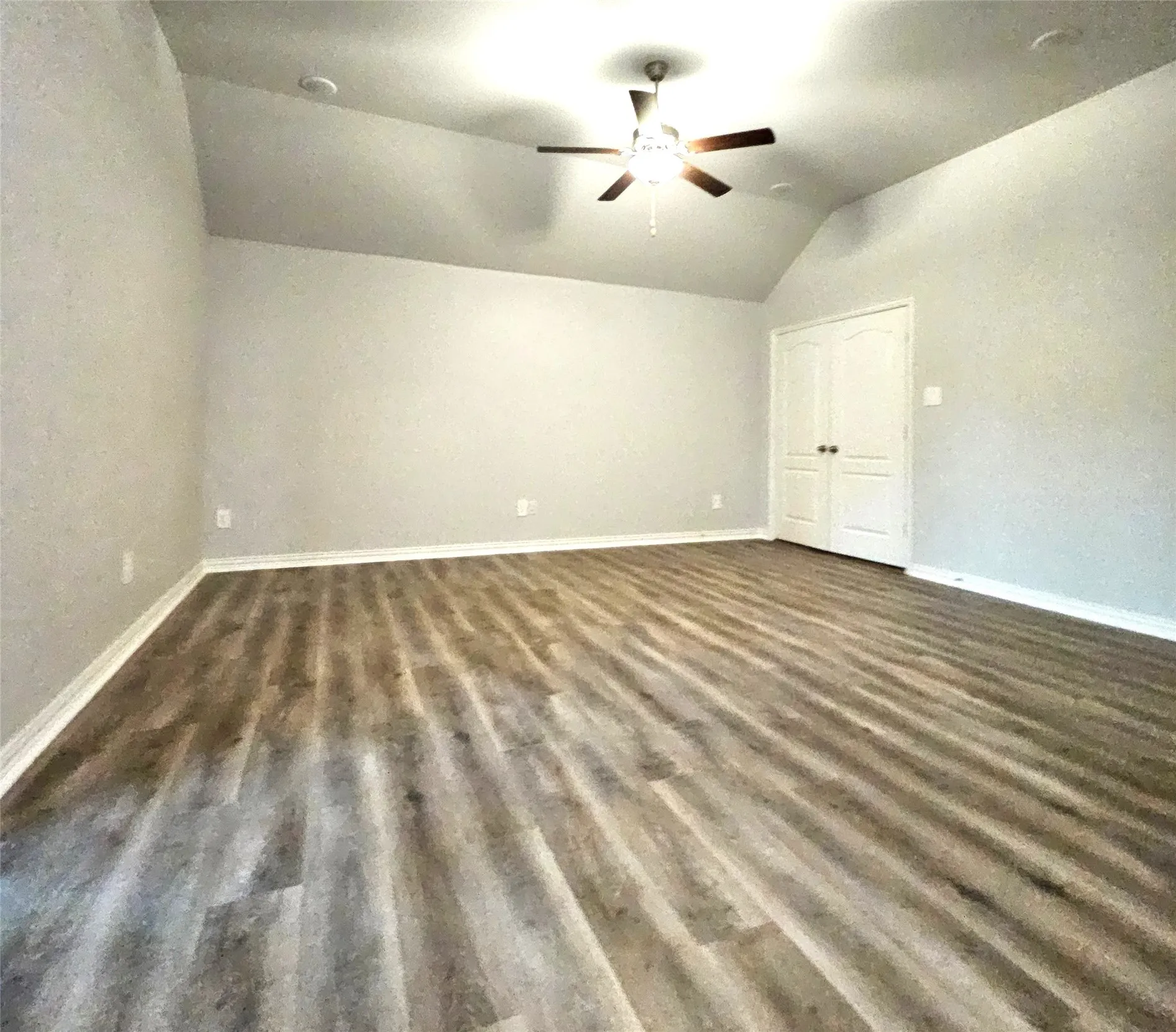 Vaulted ceiling with a ceiling fan, wood-finish flooring, recessed lighting, and double-panel doors