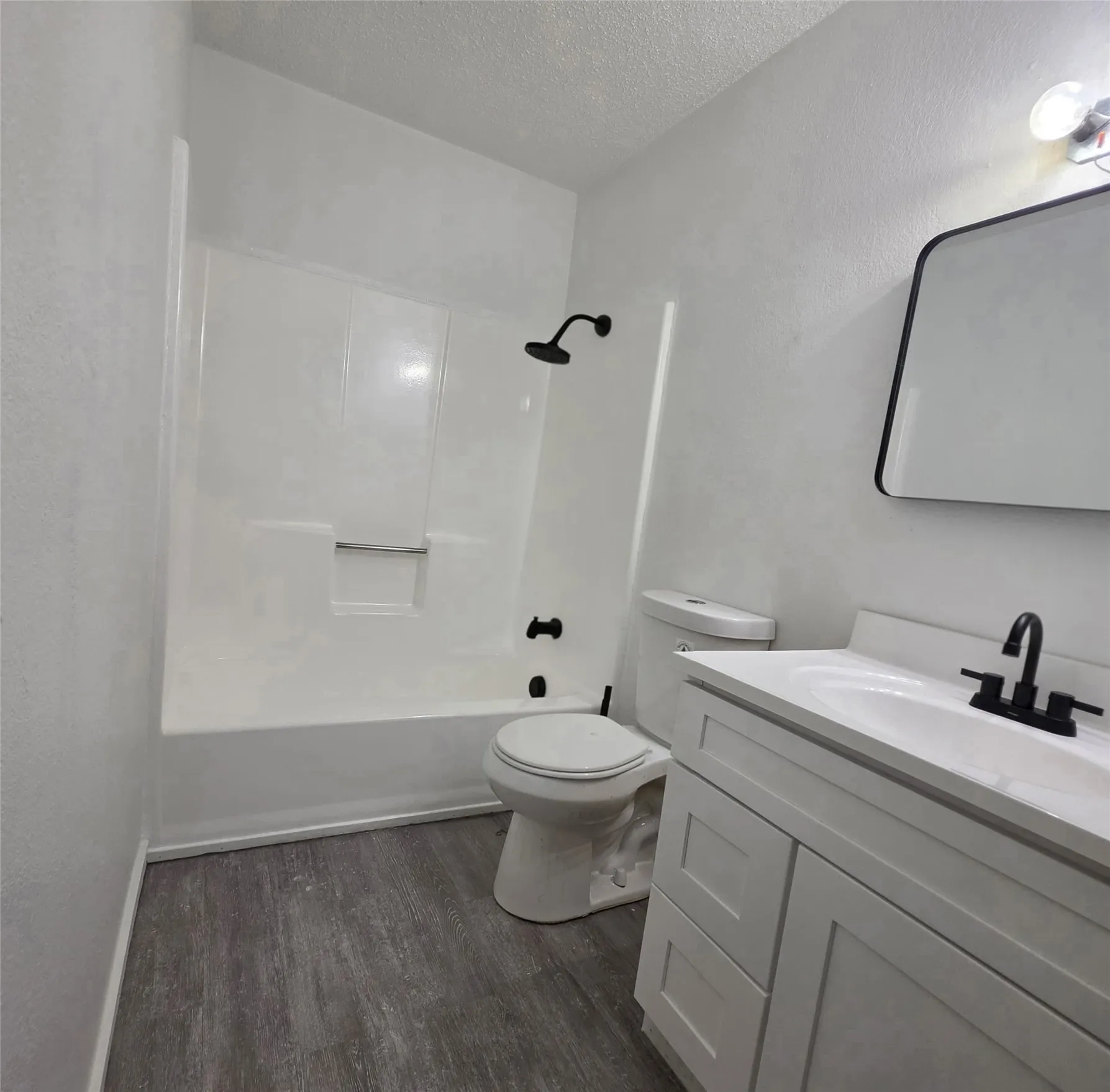 White vanity with an integrated sink, matte black faucet, and frameless mirror with a black border