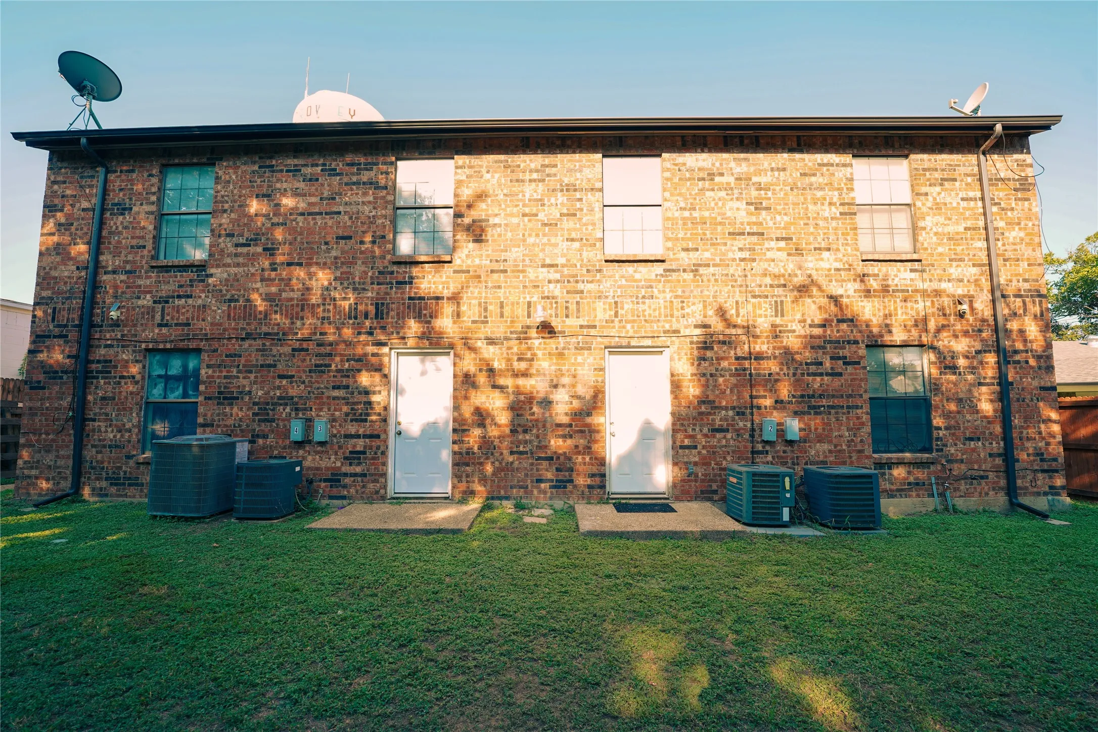Back of property featuring a yard and brick siding
