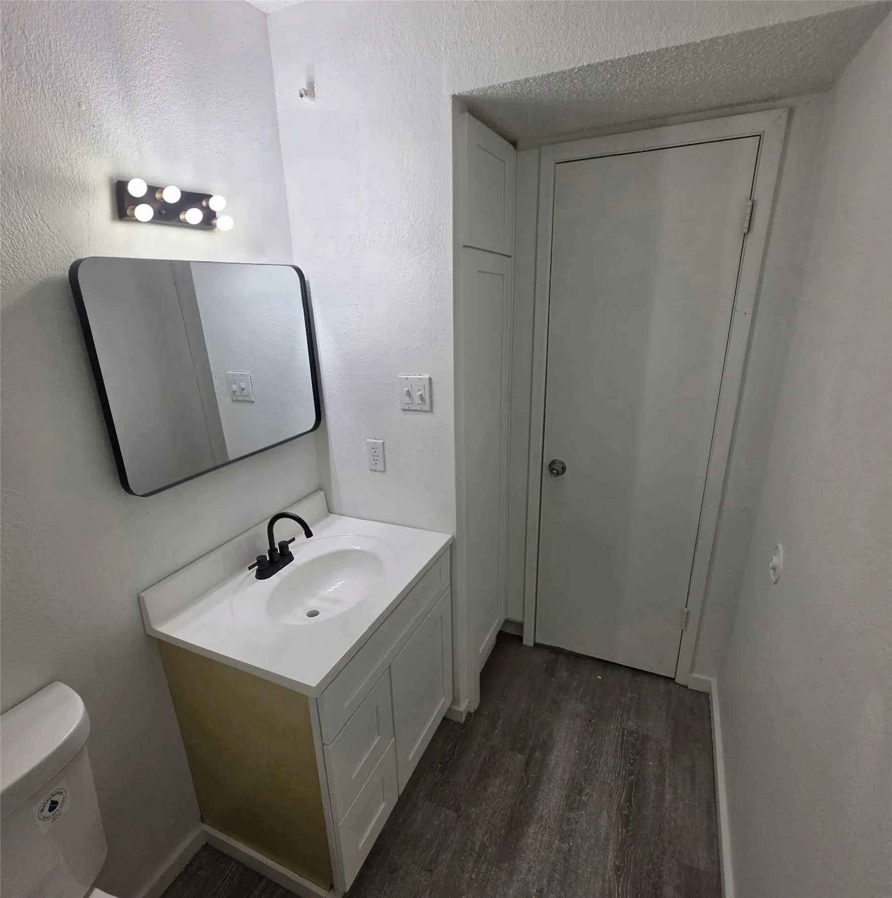Vanity with integrated sink, matte black faucet, and frameless mirror