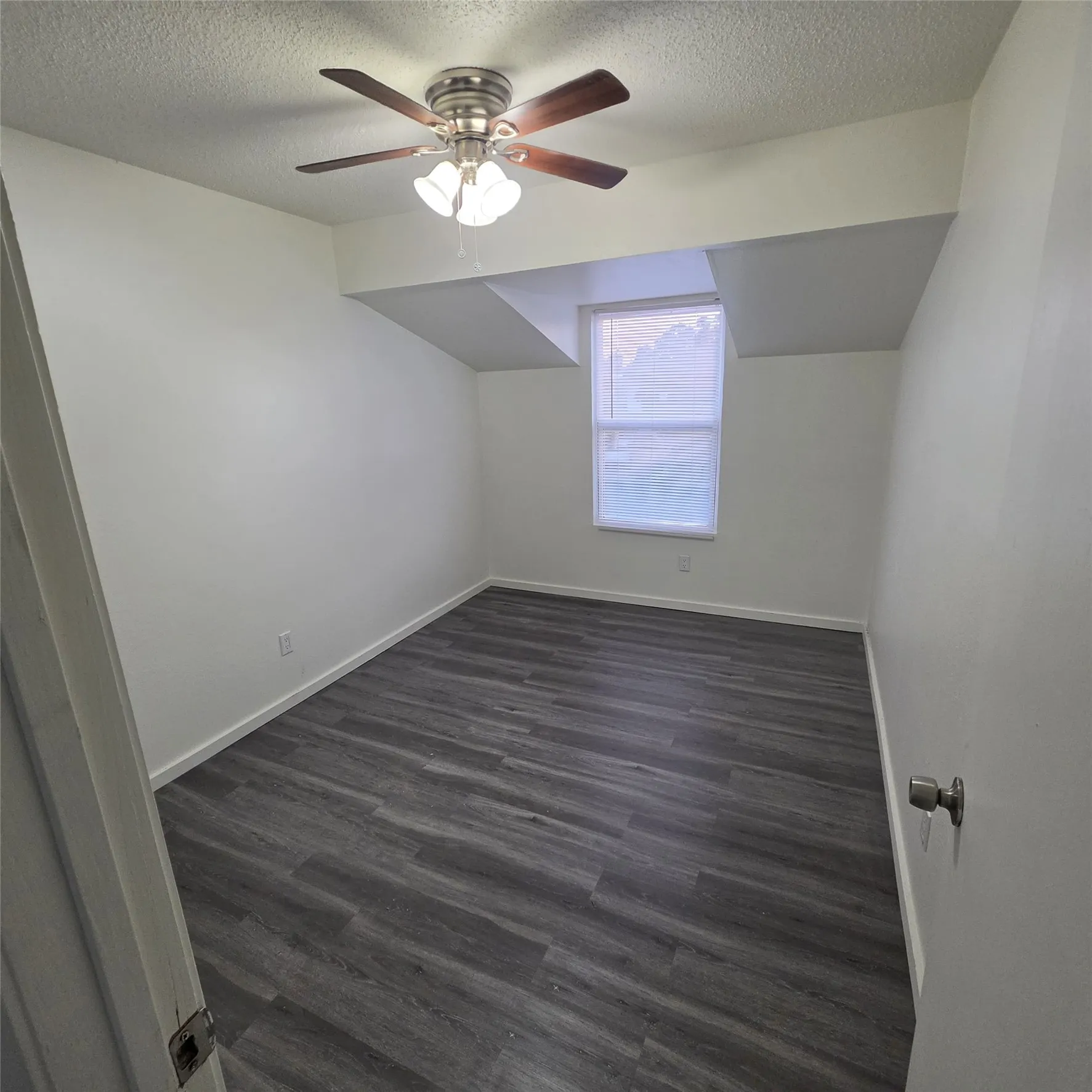 Wood-finish flooring, ceiling fan with integrated lighting, and a single window with blinds
