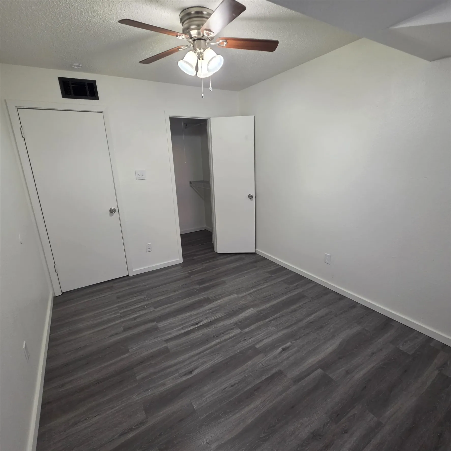 Wood-finish flooring, ceiling fan with integrated lighting, and white walls