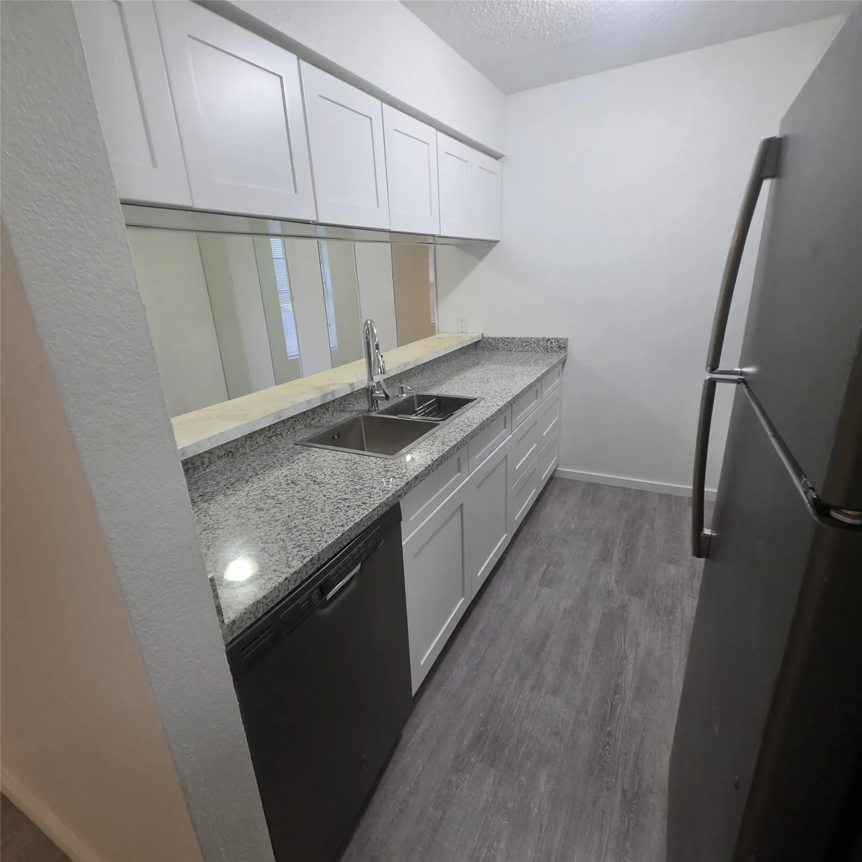 Kitchen featuring white shaker-style cabinetry, a stainless steel double basin sink with a high-arc faucet, and granite countertops