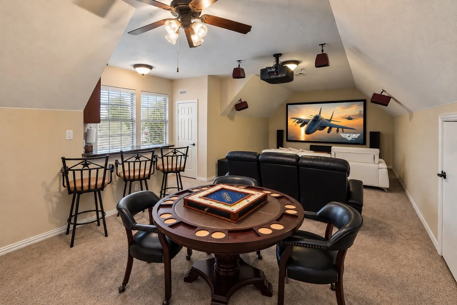 Media room with a ceiling-mounted projector, integrated screen, and built-in wet bar