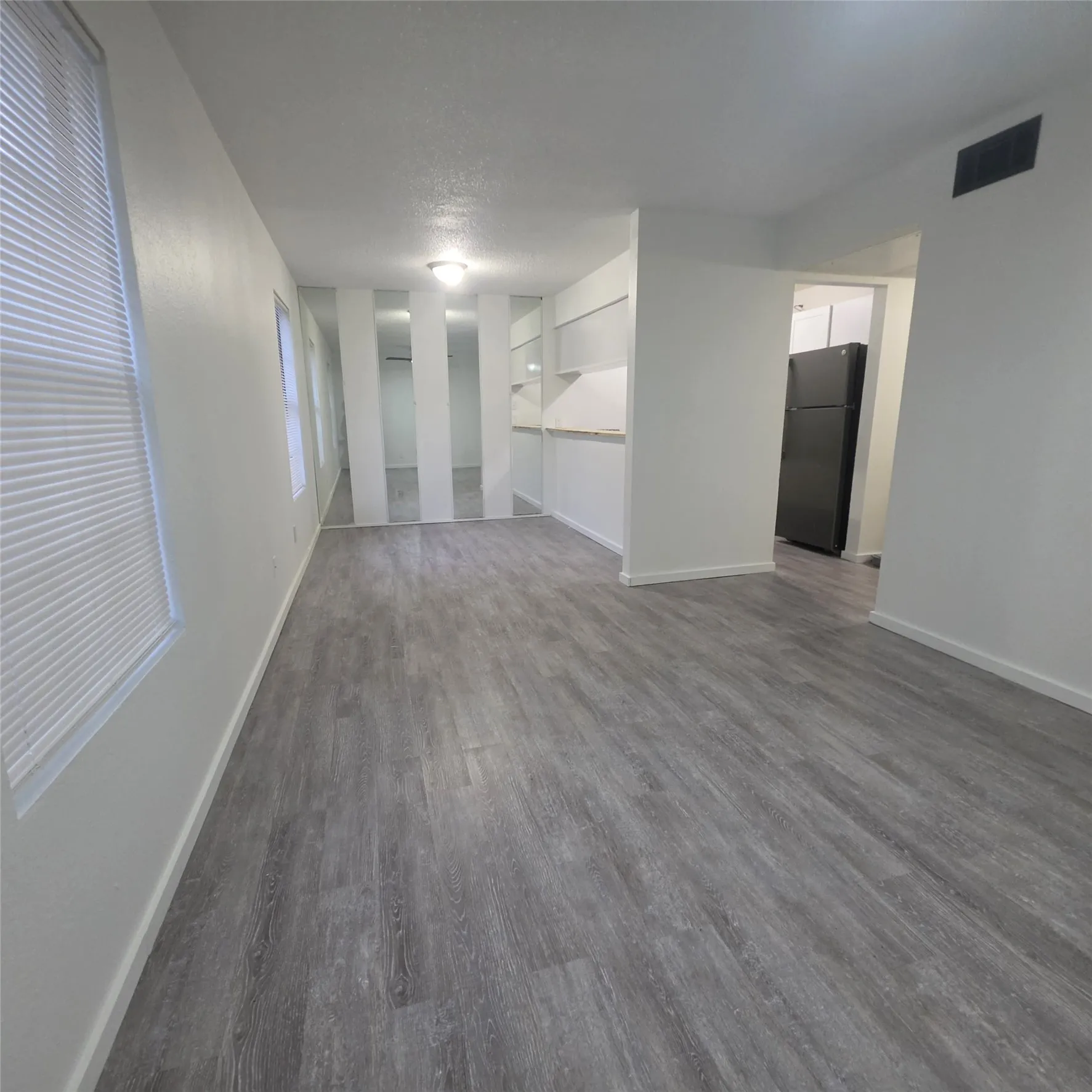 Wood-finish flooring throughout, white walls, and a recessed ceiling light