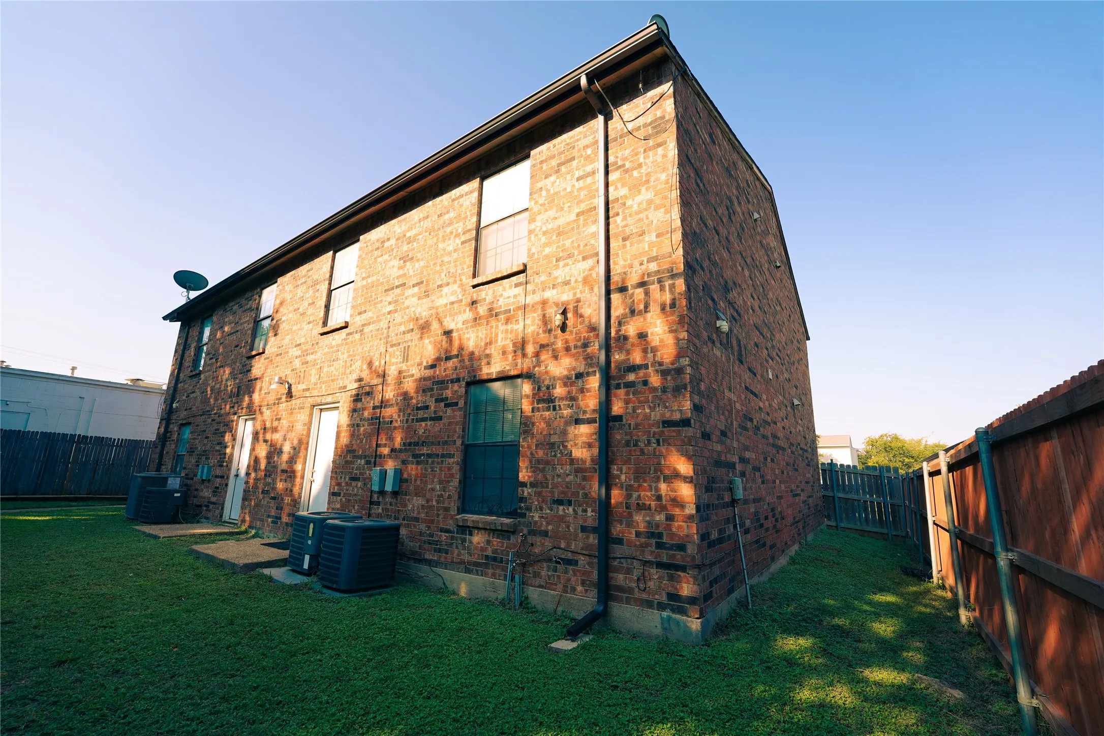 View of property exterior featuring brick siding and a fenced backyard