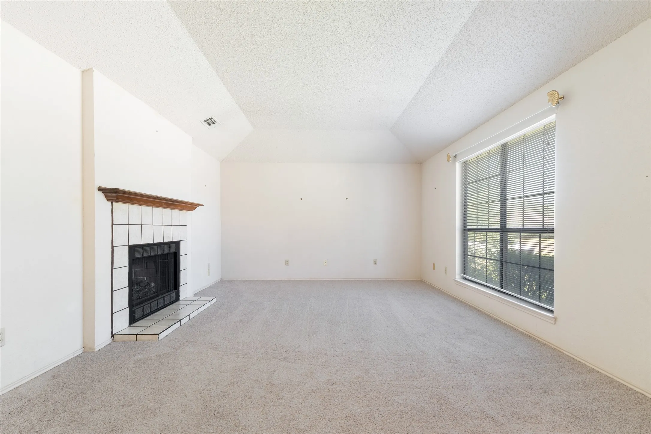 A very spacious living room with a wood burning fireplace.