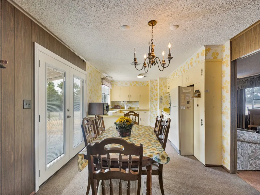 Dining area featuring a chandelier, wood-finish wall paneling, and glass-paned double doors