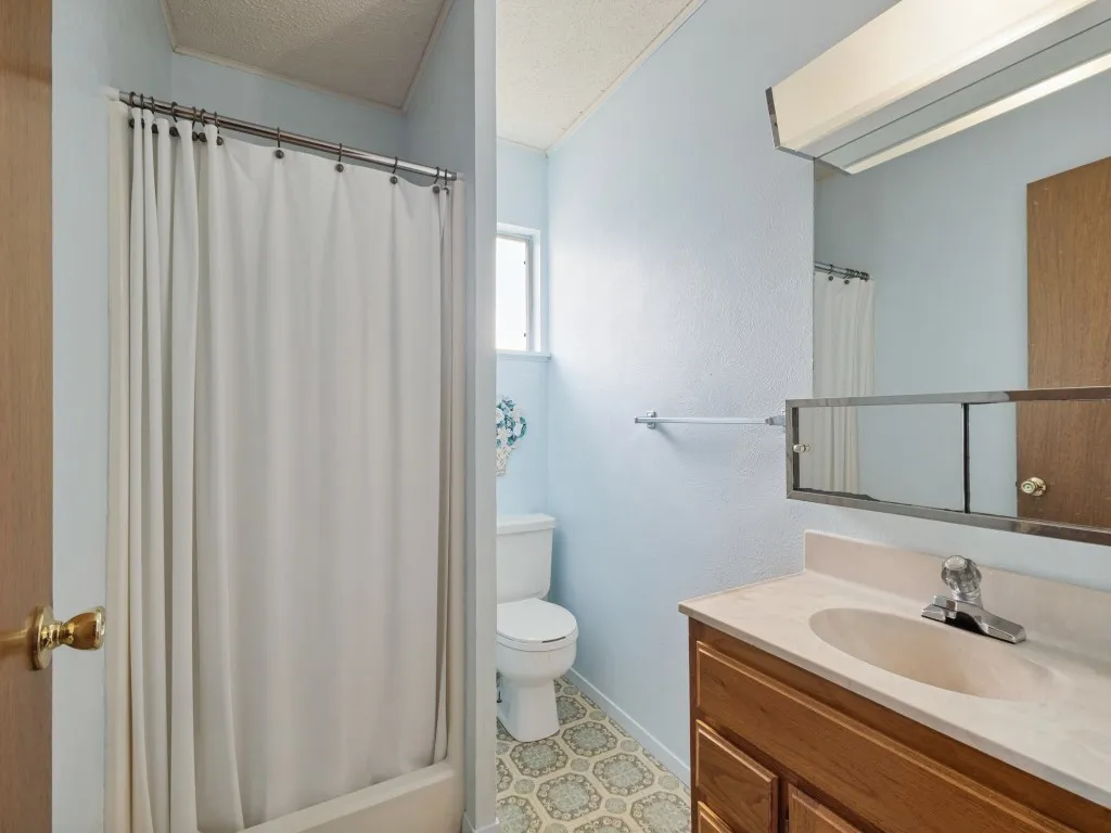 The primary bathroom features a single shower, mirror-front medicine cabinets and a charming, patterned flooring.