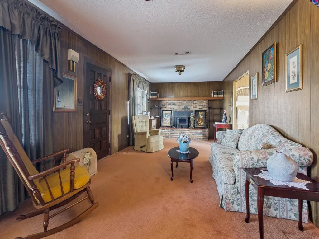 Living room featuring wood paneling and a brick-surround fireplace