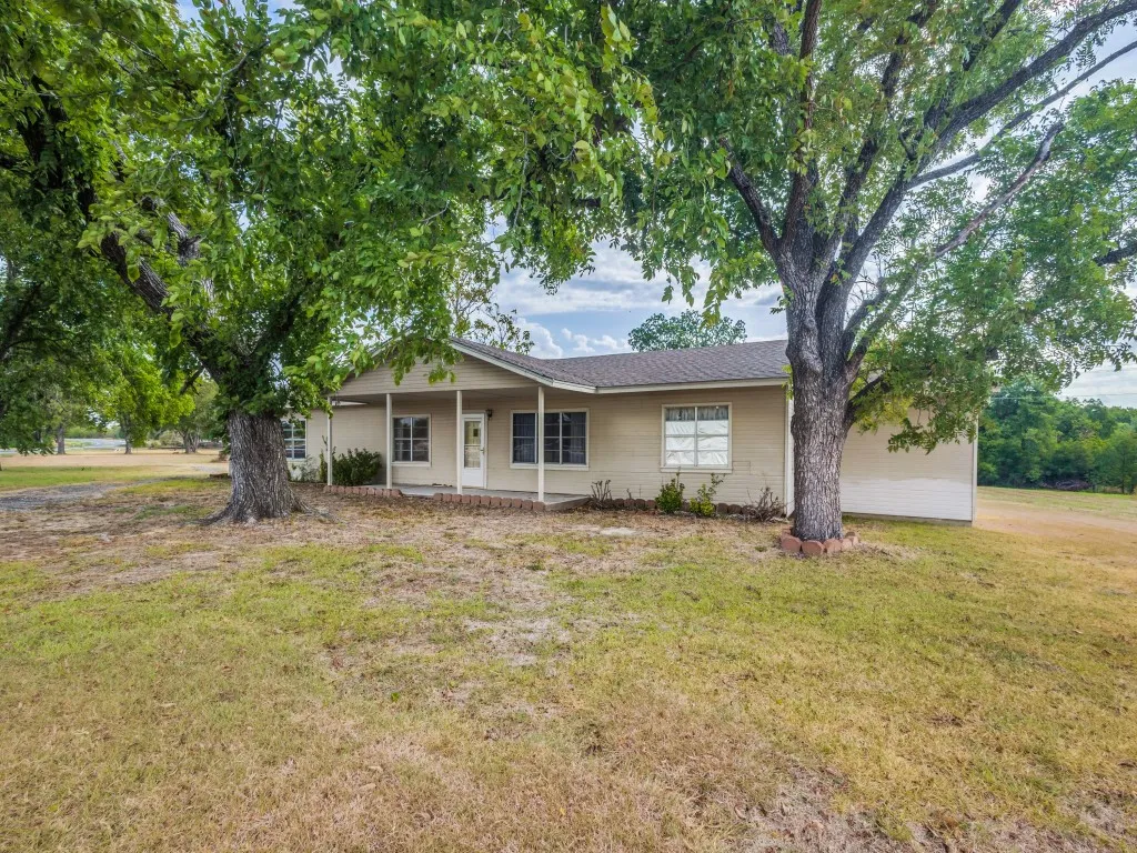 Single-story ranch-style home featuring a covered front porch and lots of windows.  Mature trees provide extra shade.