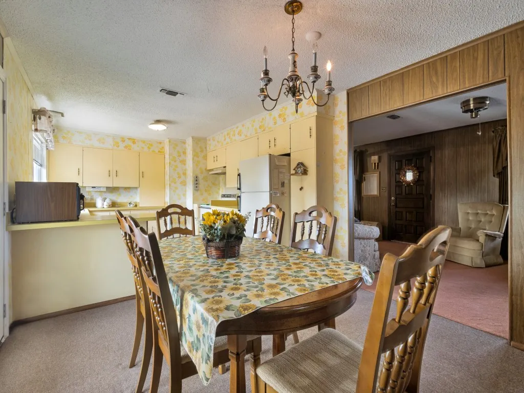 Open-concept kitchen and dining area featuring painted cabinetry, a breakfast bar, and an overhead chandelier