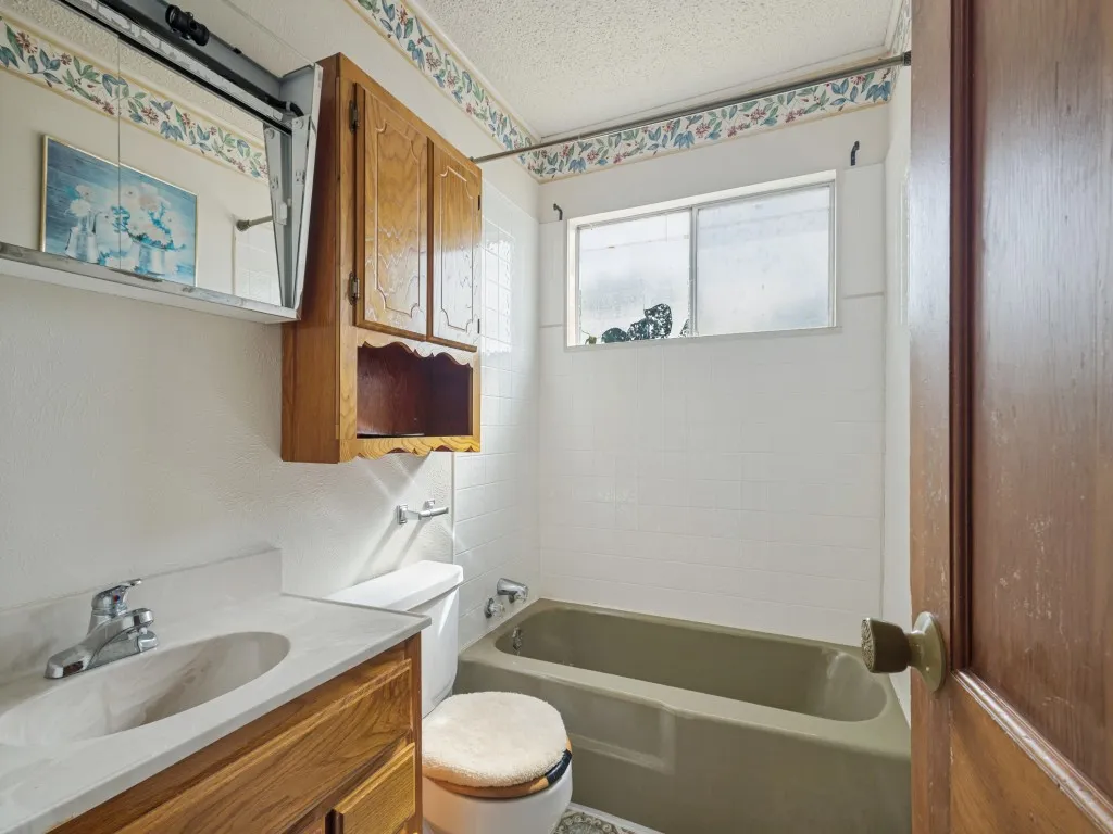 Hallway bathroom features a mirror with built-in storage and additional storage above the toilet.
