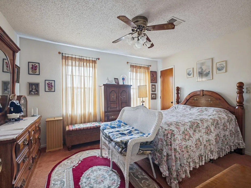 The primary bedroom is located at the end of the hallway.  It has a ceiling fan and large windows.
