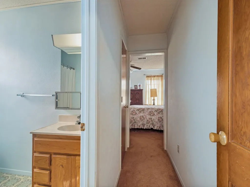 View from hallway of primary bedroom and bathroom with a storage closet on the left.