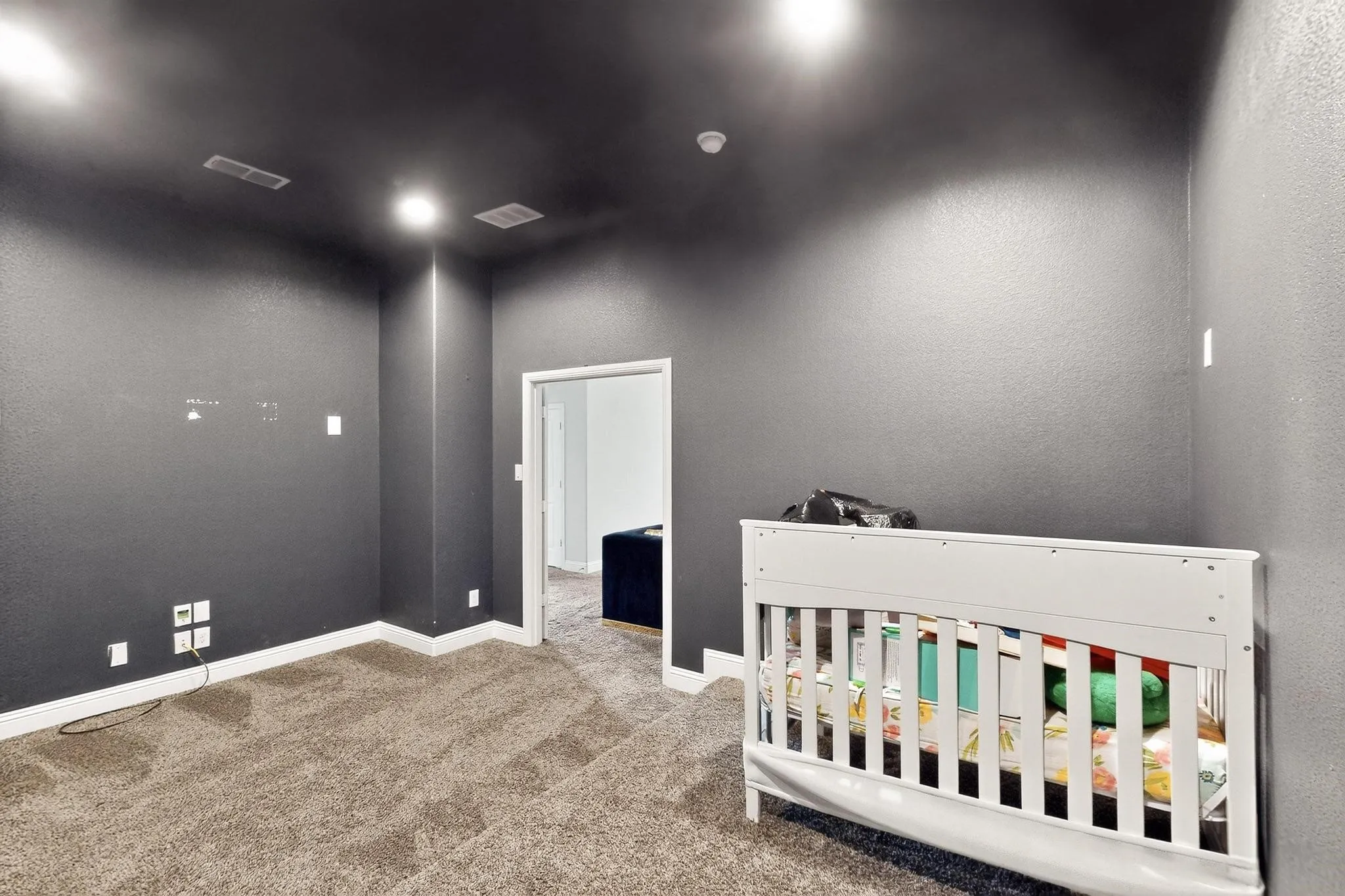Carpeted bedroom with a textured wall and a nursery area