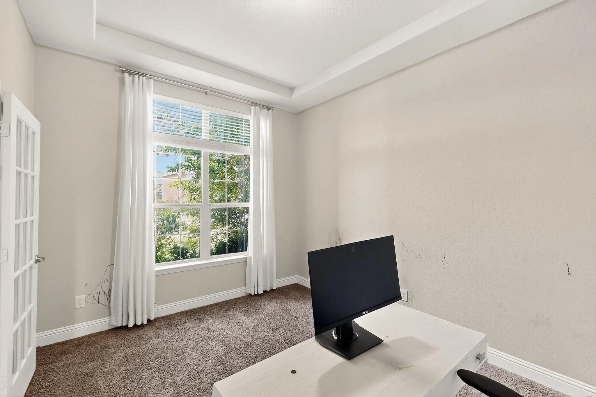 Carpeted office space with a tray ceiling