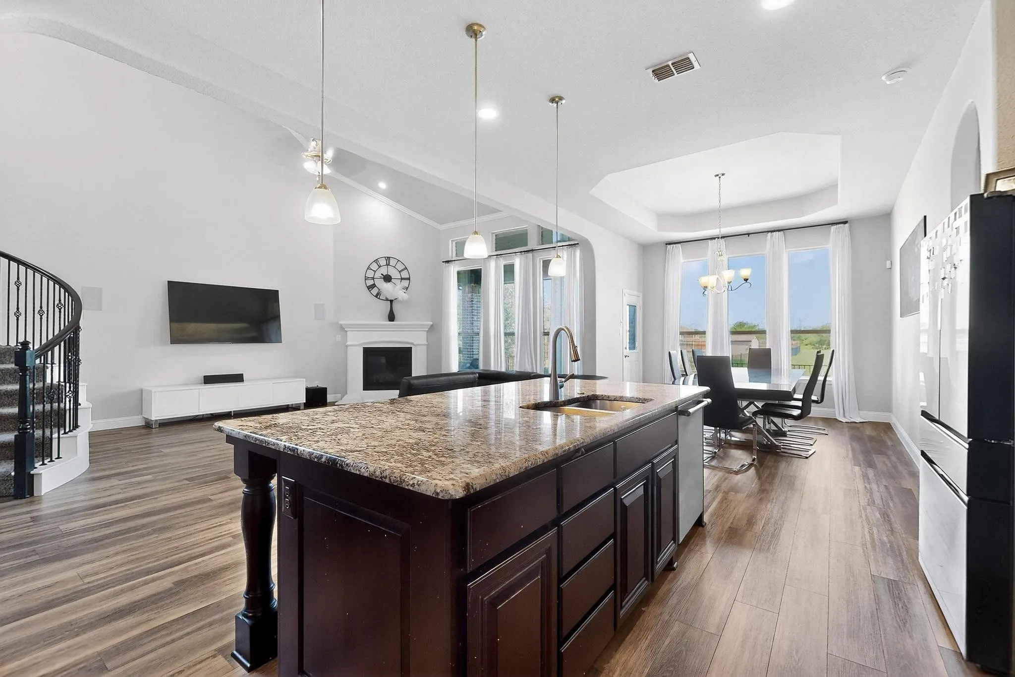 Kitchen with dark brown cabinetry, a glass covered fireplace, pendant lighting, light stone countertops, and freestanding refrigerator