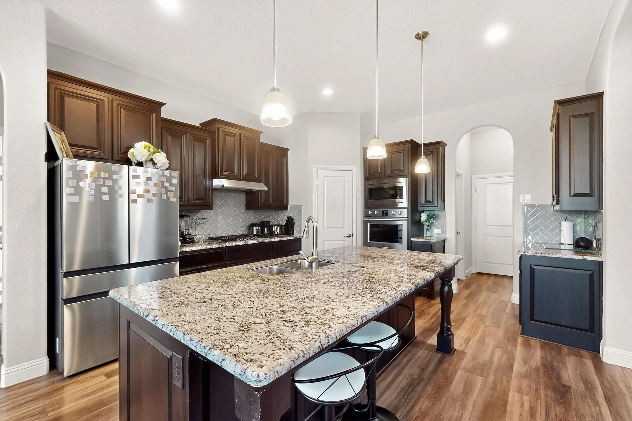 Kitchen featuring dark brown cabinets, stainless steel appliances, a breakfast bar, hanging light fixtures, and recessed lighting