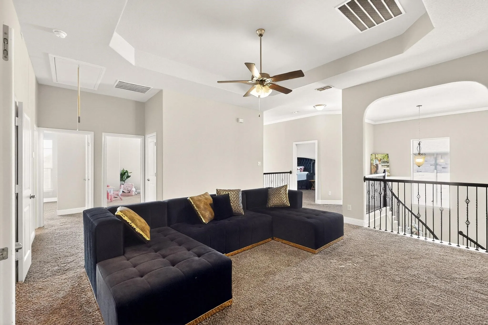 Carpeted living area with a raised ceiling, attic access, and ceiling fan
