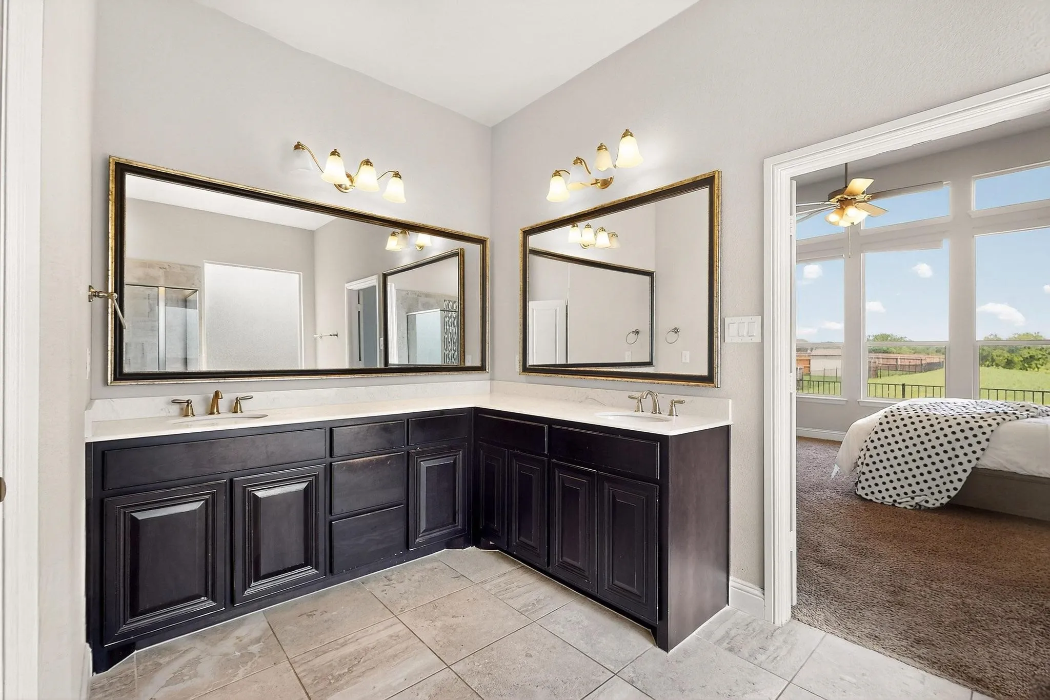 Ensuite bathroom featuring double vanity, light tile patterned flooring, a ceiling fan, and an enclosed shower