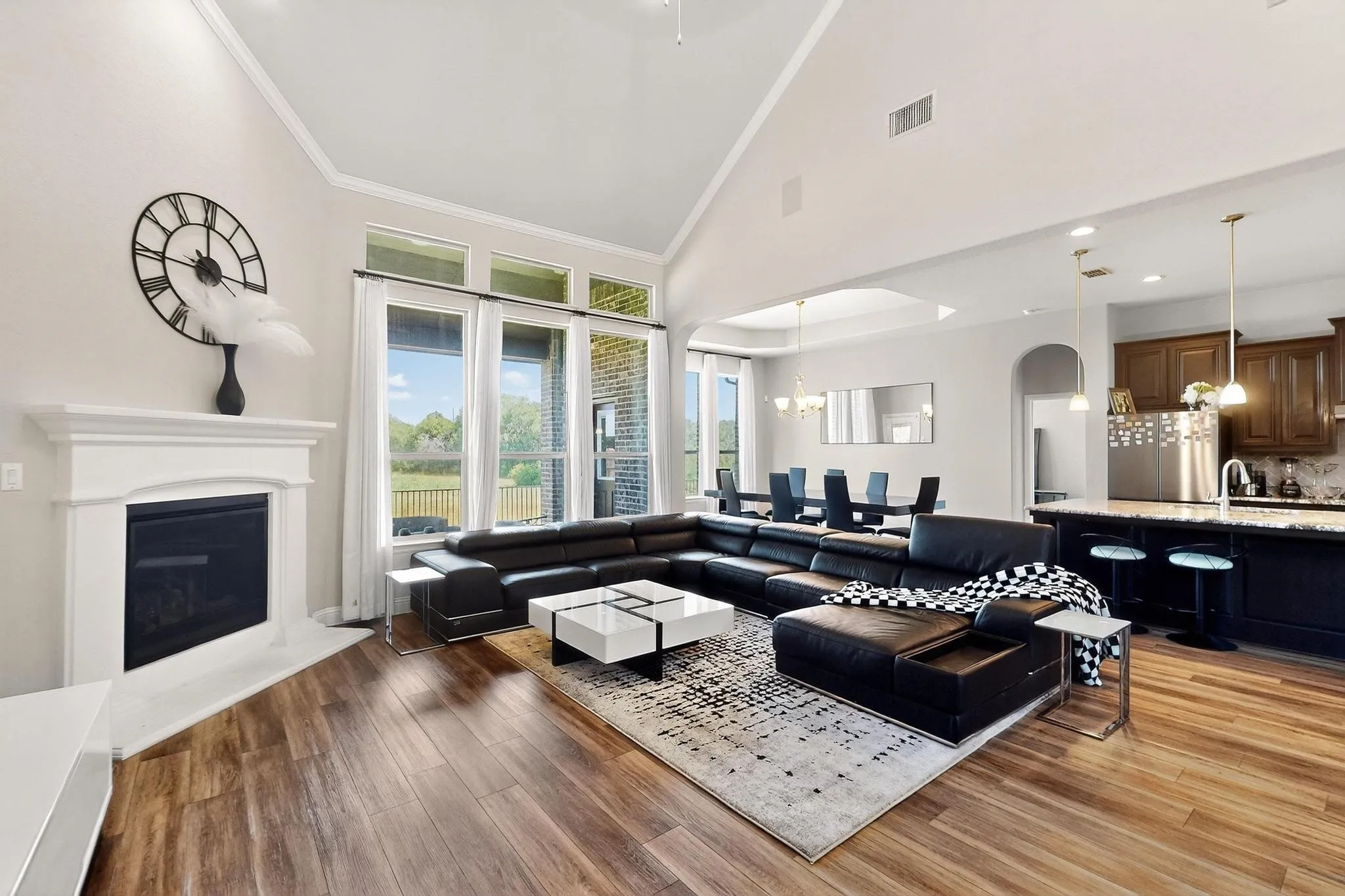 Living room featuring high vaulted ceiling, a chandelier, a glass covered fireplace, light wood-style flooring, and crown molding