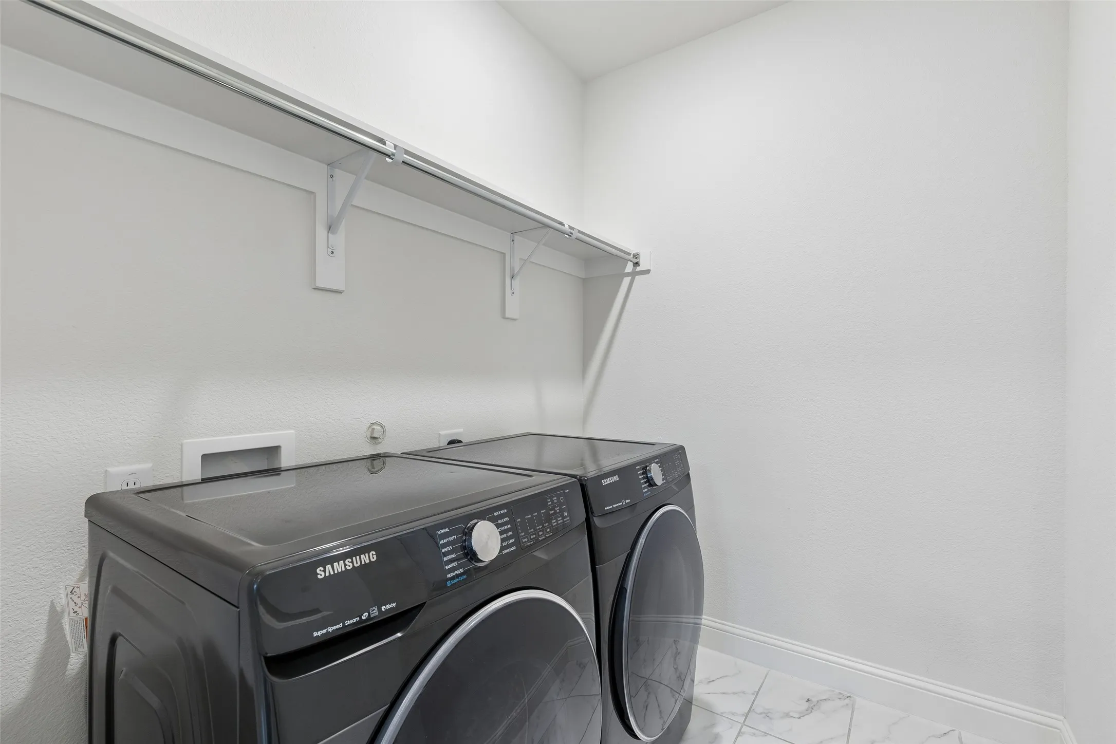 Close the door on laundry day, with shelving above keeping detergent and everyday essentials right where you need them.