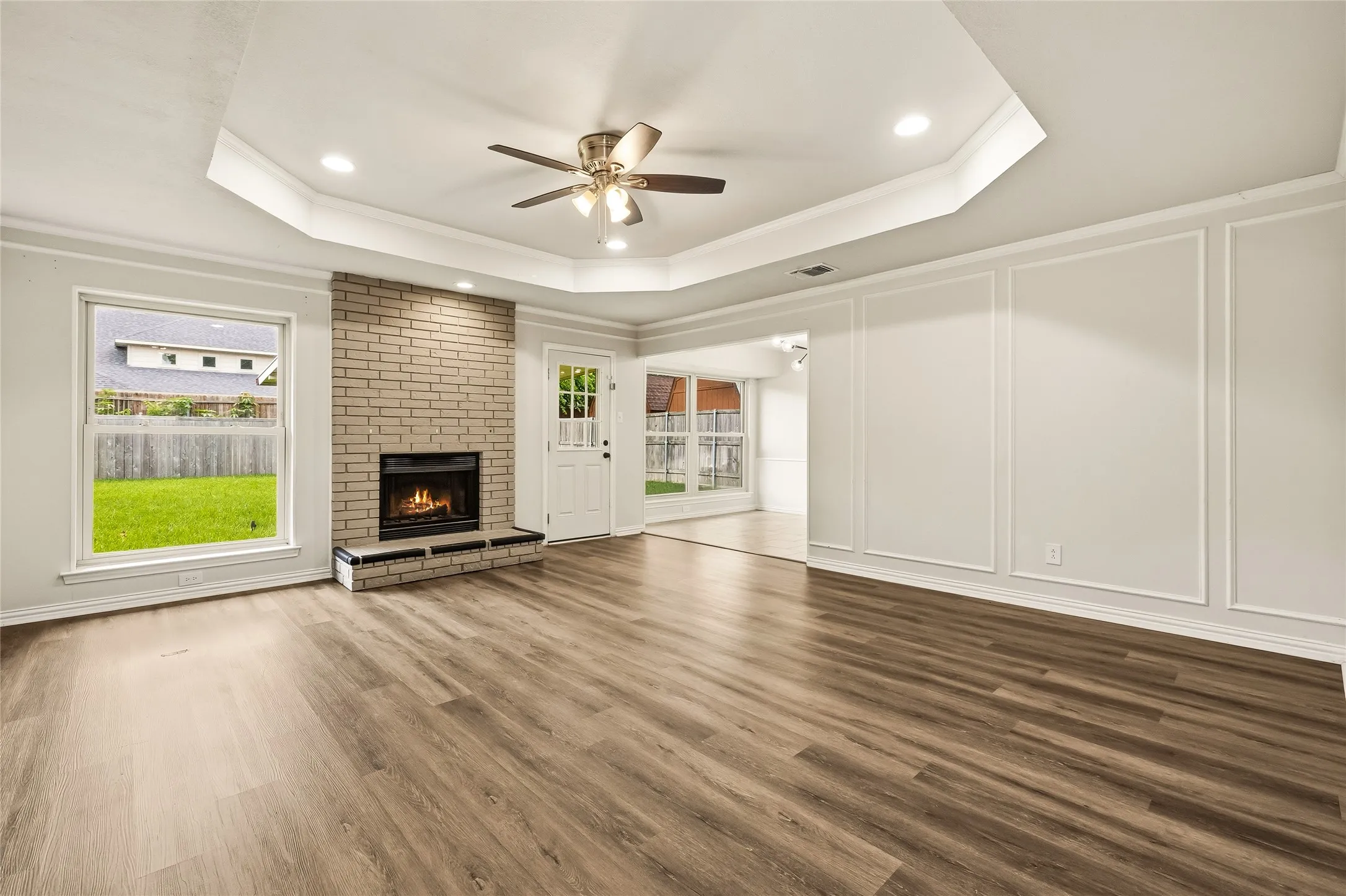 Expansive living room with large windows, fireplace, and tray ceiling