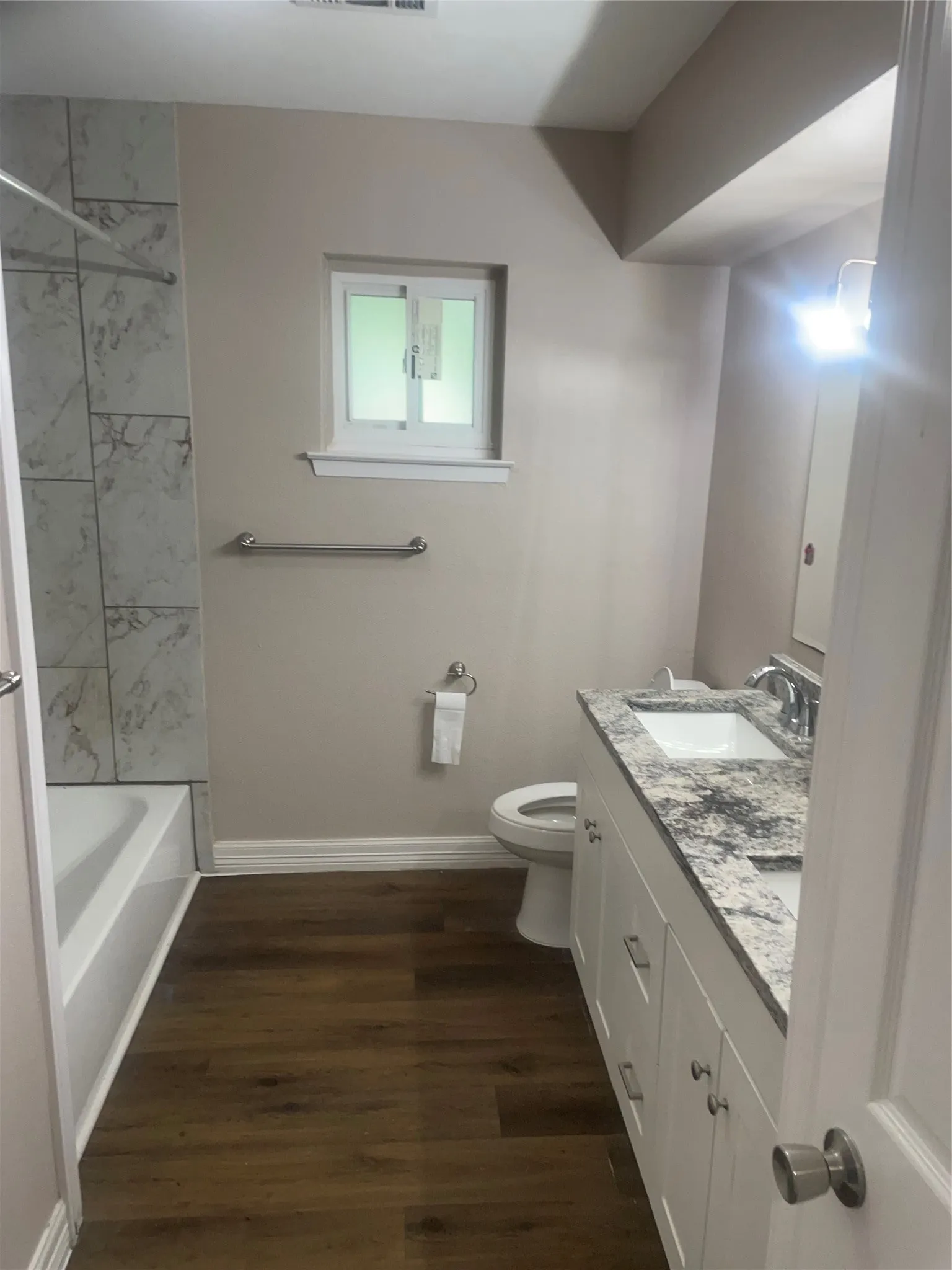 White vanity with dual sinks, a stone-finish countertop, and stainless steel hardware