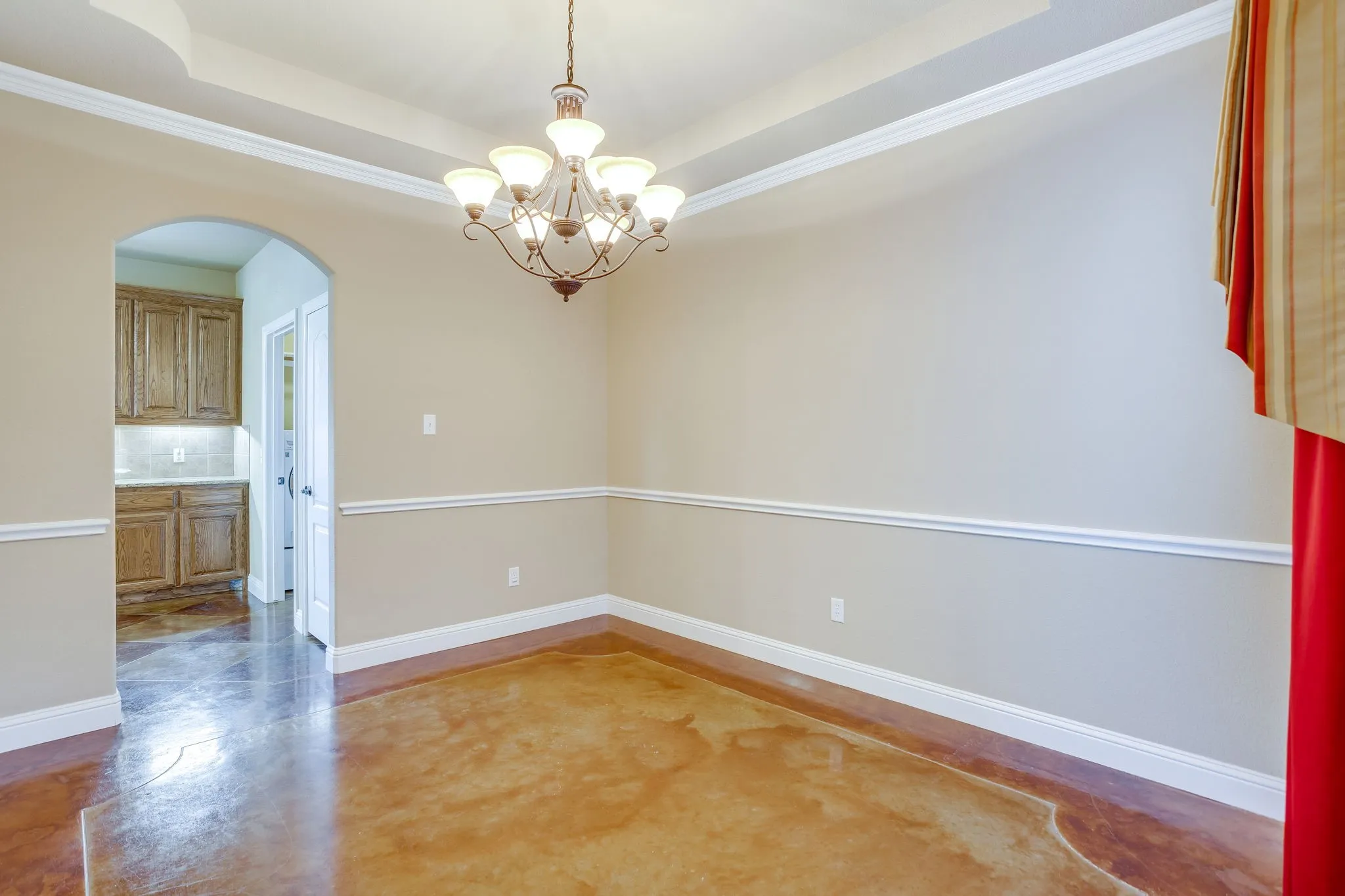 Formal dining room with  tray ceiling, crown molding and stained and scored concrete floors.