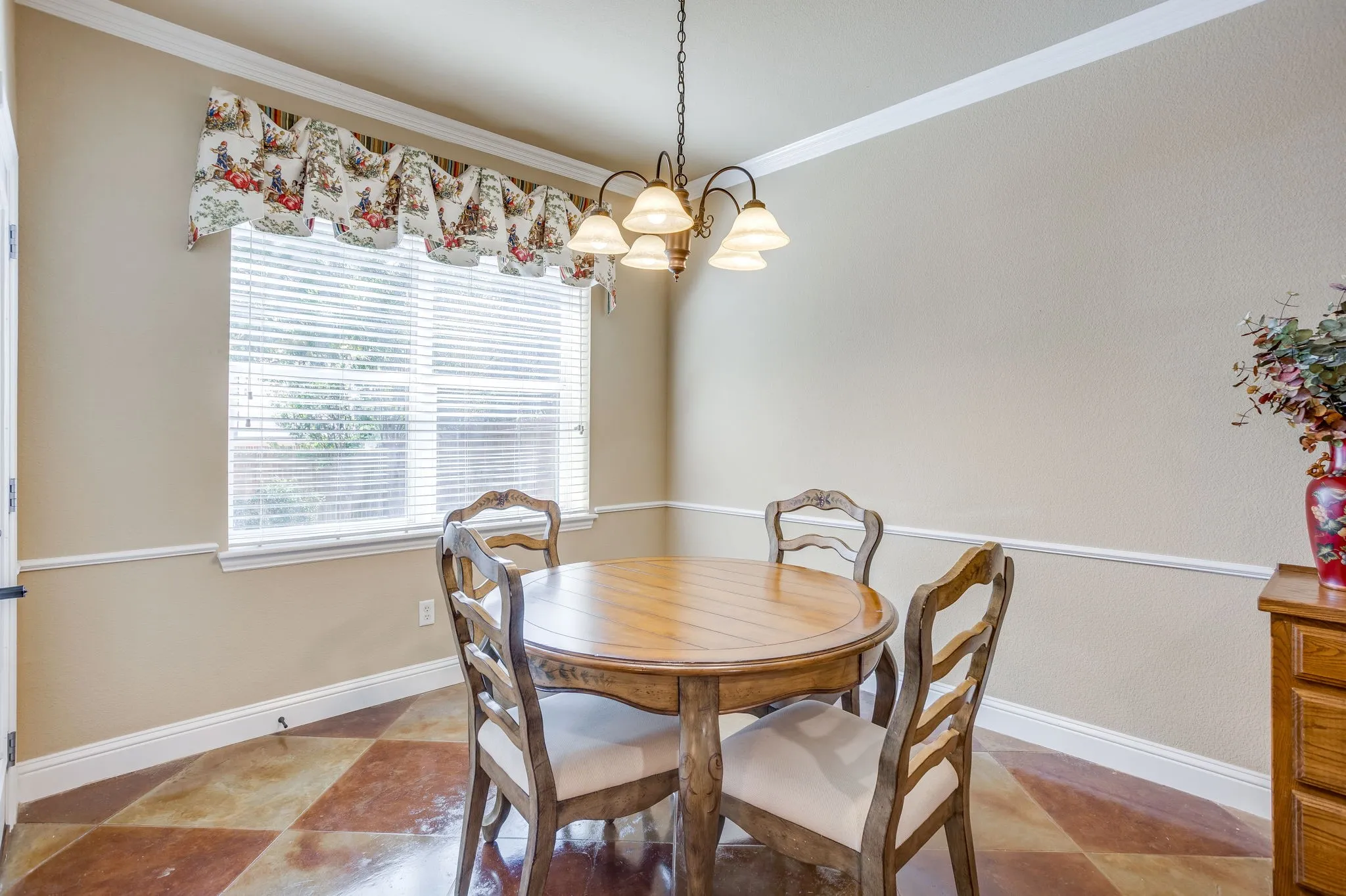 Spacious breakfast room with chandelier, window treatments, stained and scored concrete floors and access to backyard.